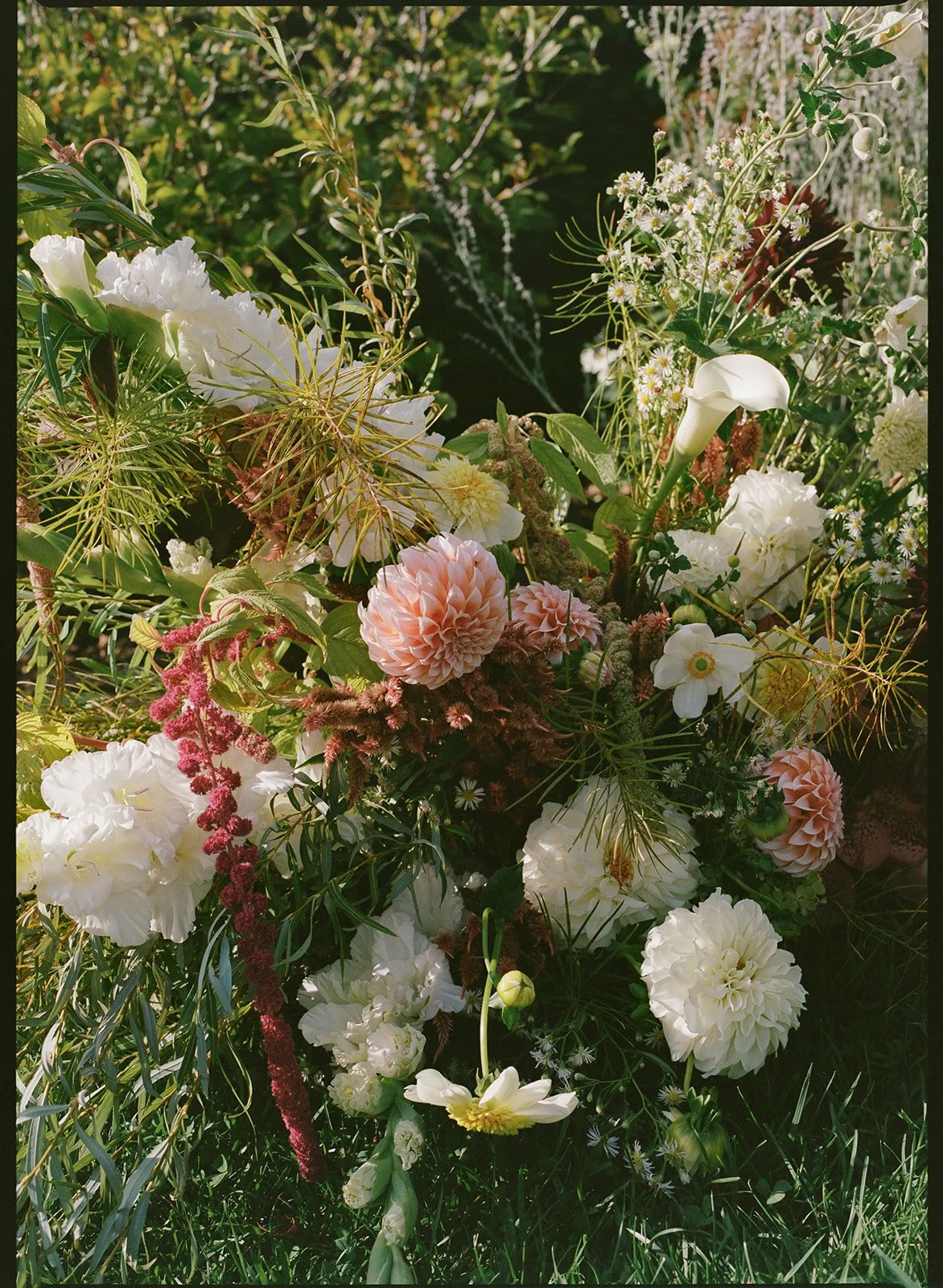 Loose, garden-style floral arrangement with layered blooms and natural texture nestled into the landscape.