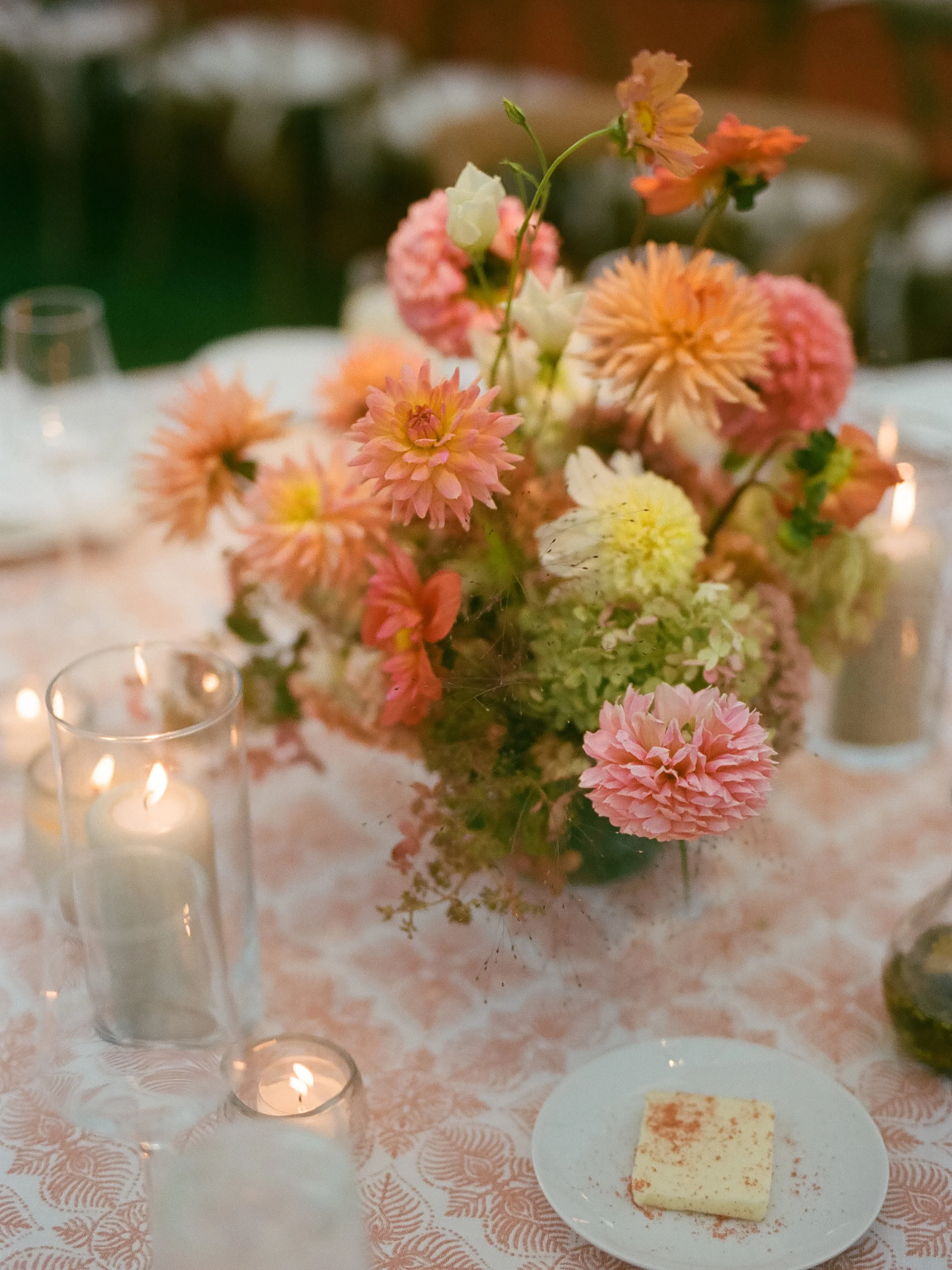 Floral centerpiece styled with candles and patterned linens on reception table