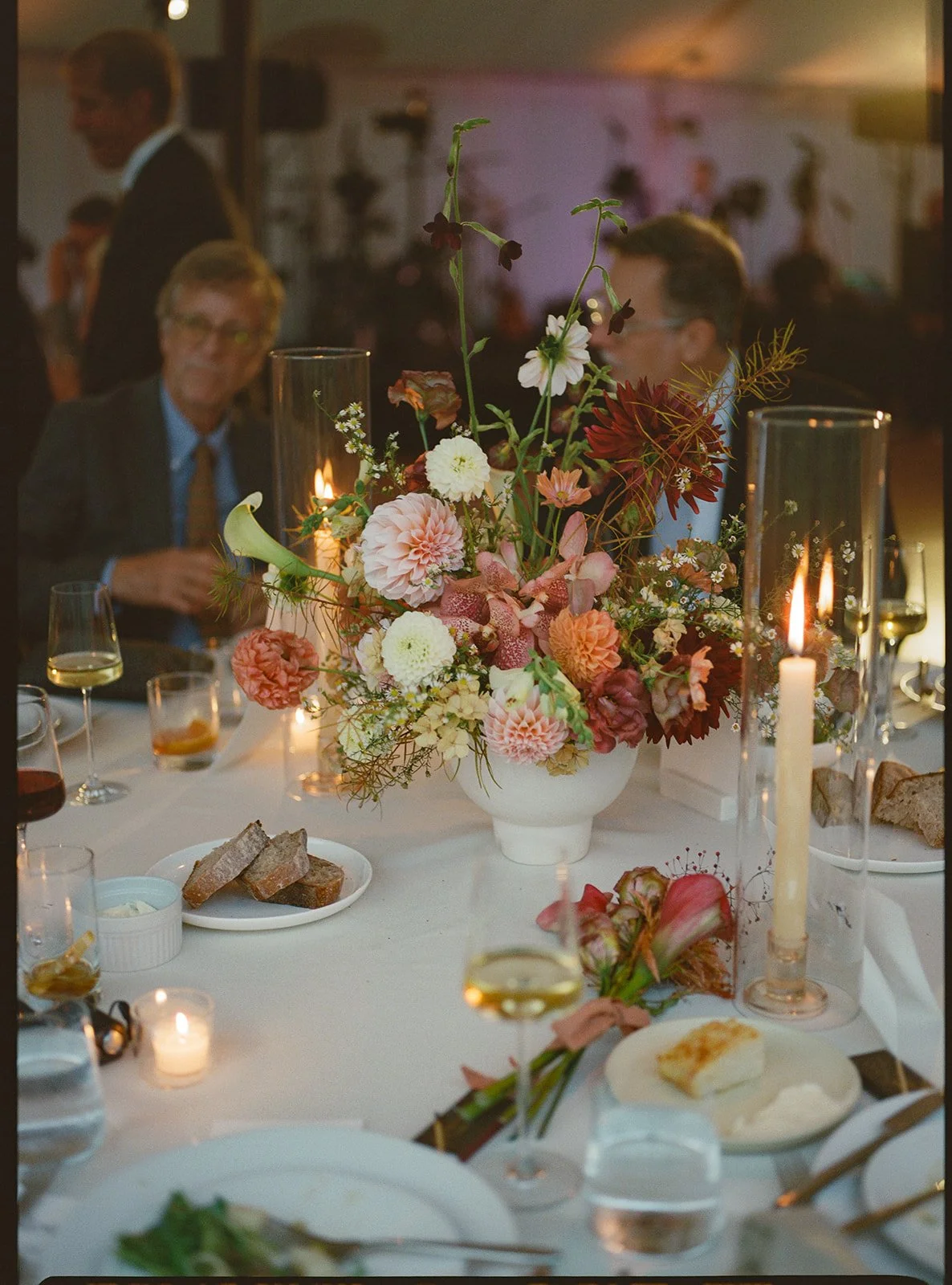 Intimate reception moment framed by glowing candles and floral arrangements down the table