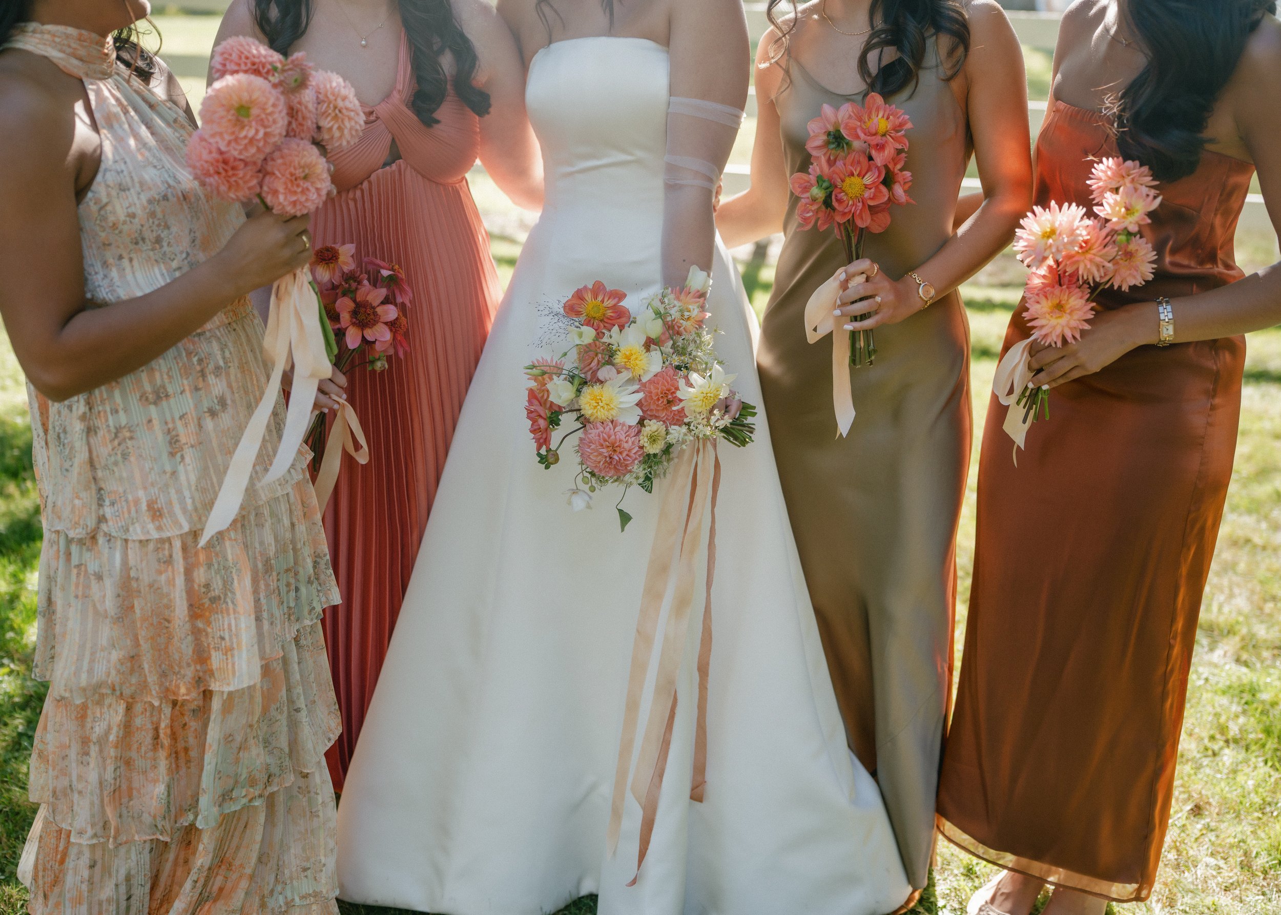 Bride and bridesmaids holding garden-style bouquets in warm autumn tones
