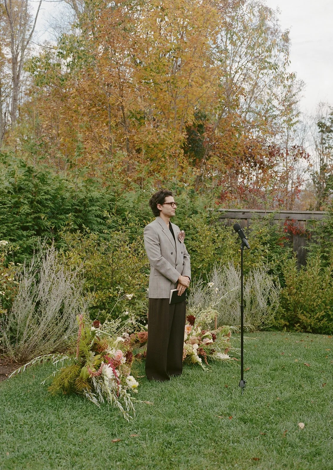 Ceremony focal arrangement of soft blush, cream, and autumn-toned flowers grounded naturally in the grass.