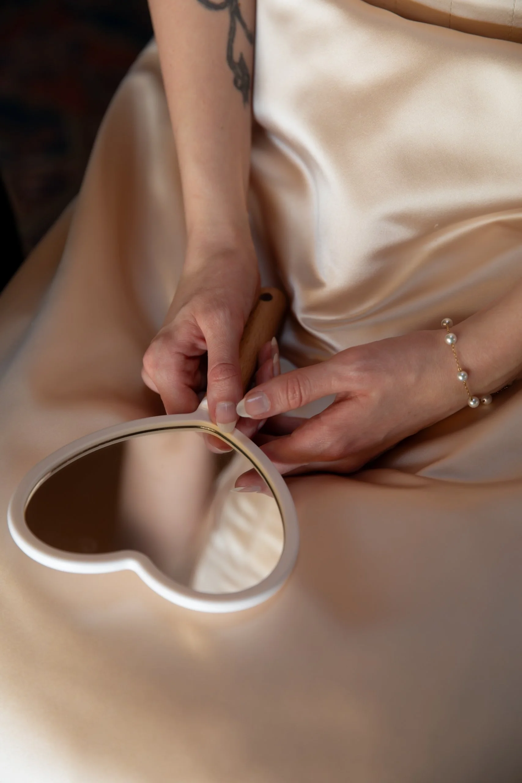 Close-up of bridal details with soft champagne fabric and heart-shaped mirror
