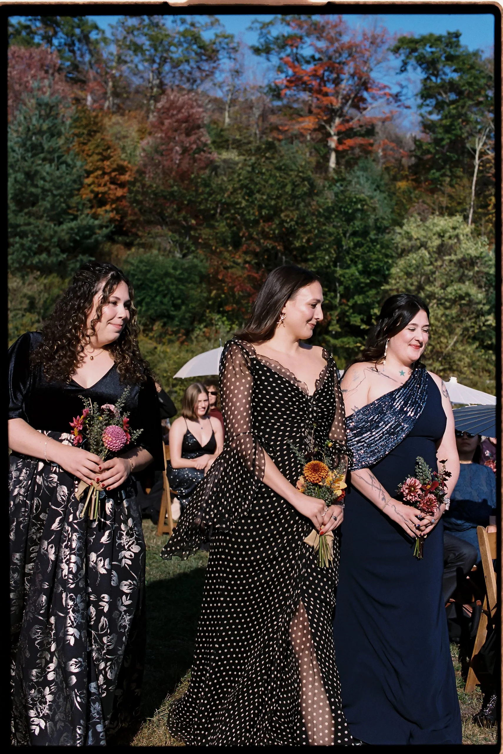 Bridesmaids carrying coordinating fall bouquets with dahlias and textural blooms during outdoor ceremony