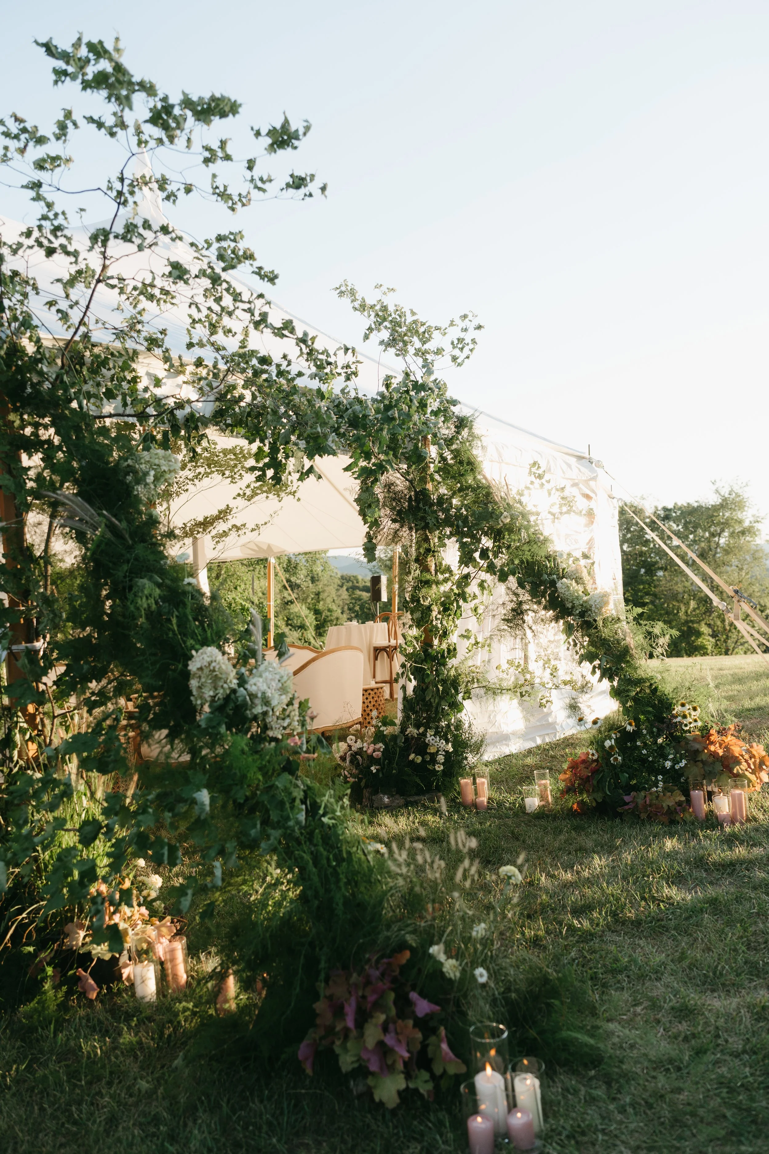 Tent entrance framed with lush asymmetrical greenery and garden-style florals leading into the reception tent