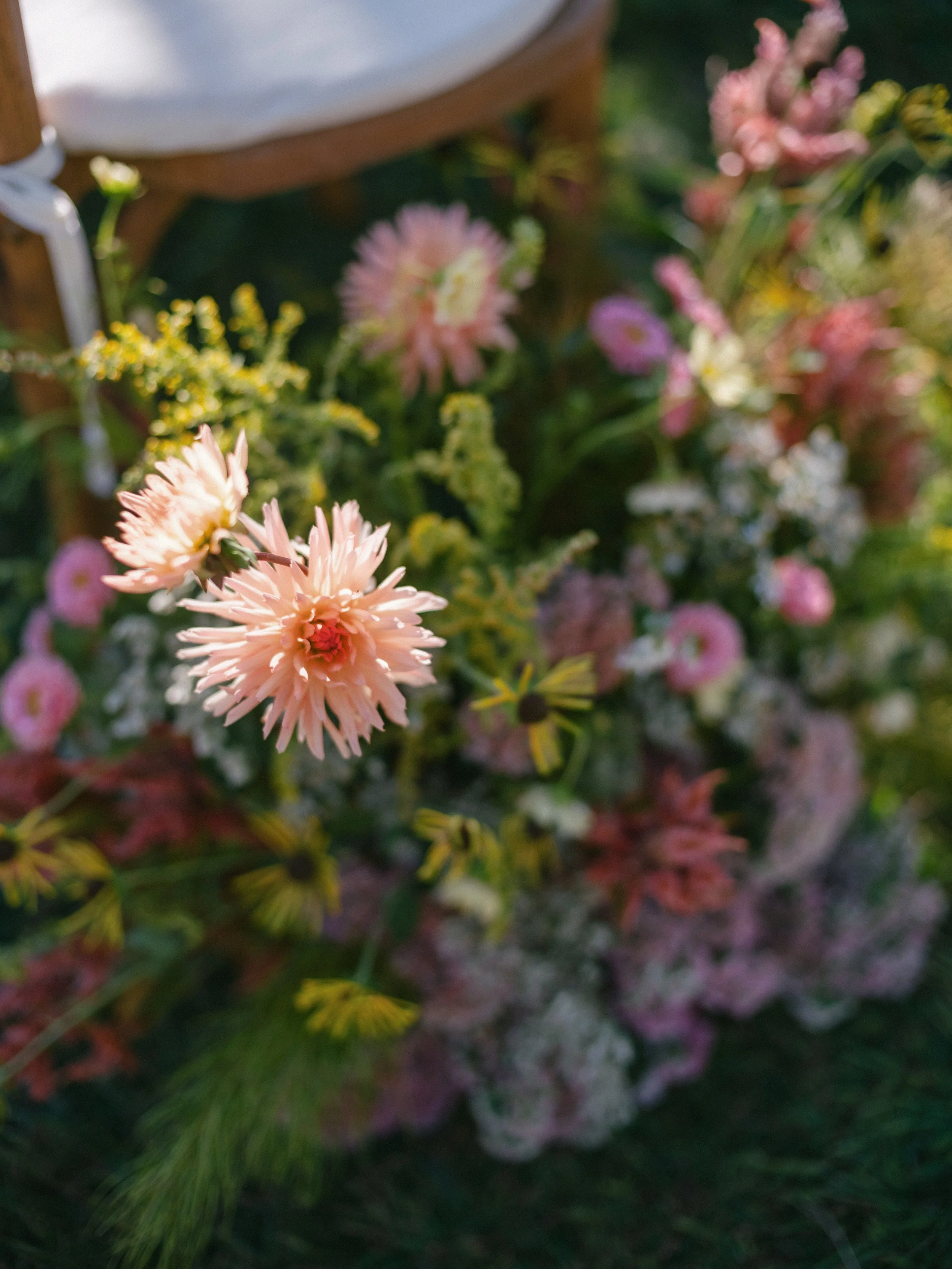 Close-up of soft pink and peach ceremony flowers tucked beside aisle seating