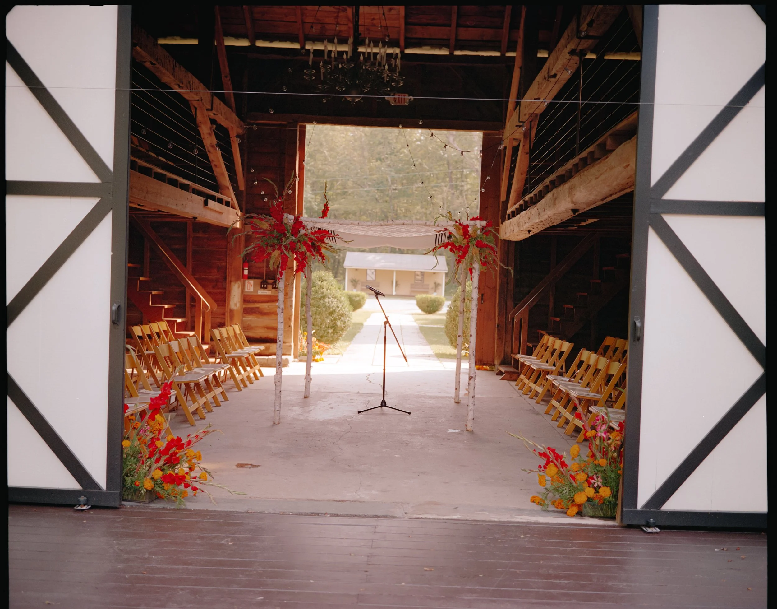 Barn ceremony setup with bold floral arrangements lining the aisle at a private estate wedding
