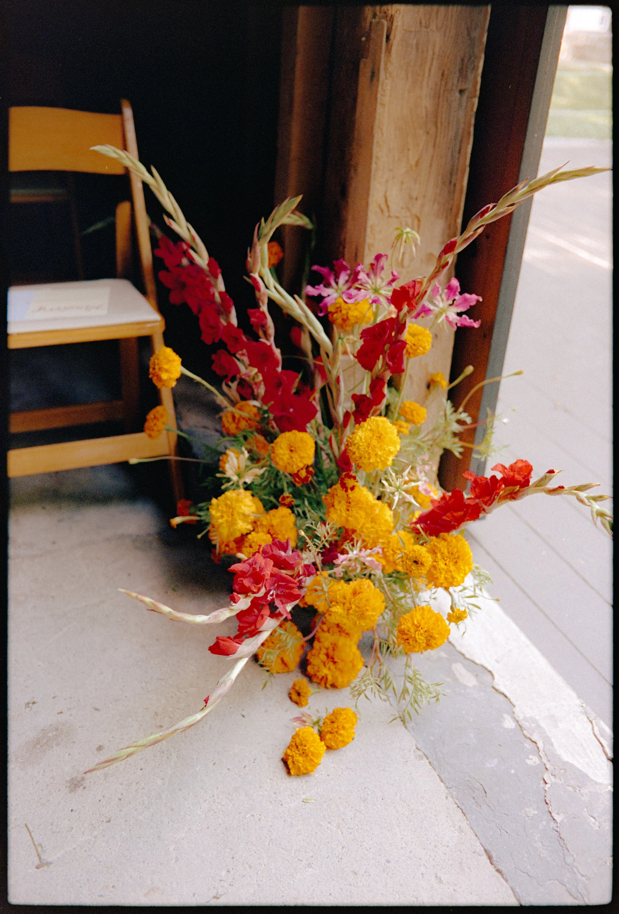 Bright red and orange ceremony flowers arranged at the barn entrance