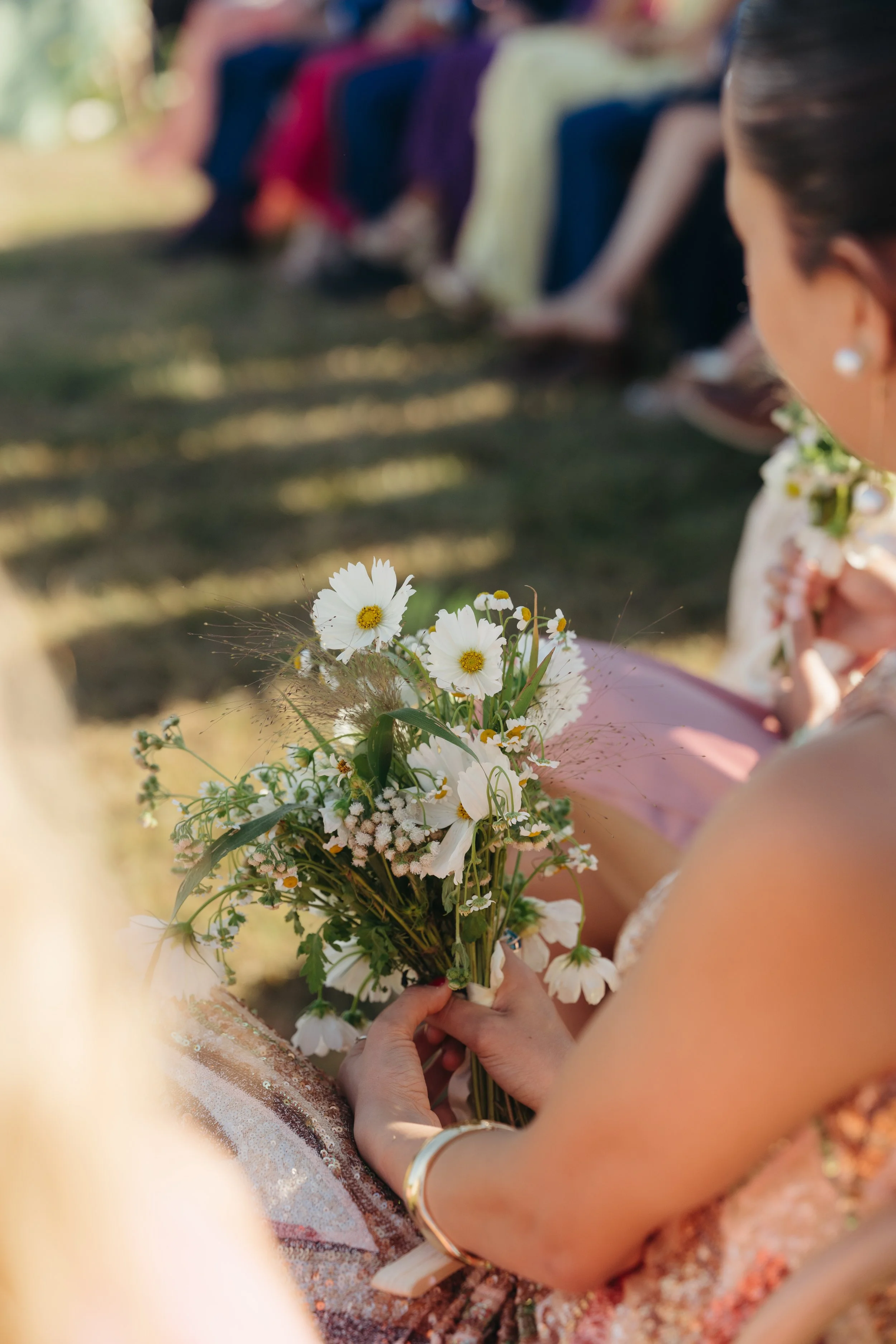 Wedding guest seated during ceremony holding small white bouquet