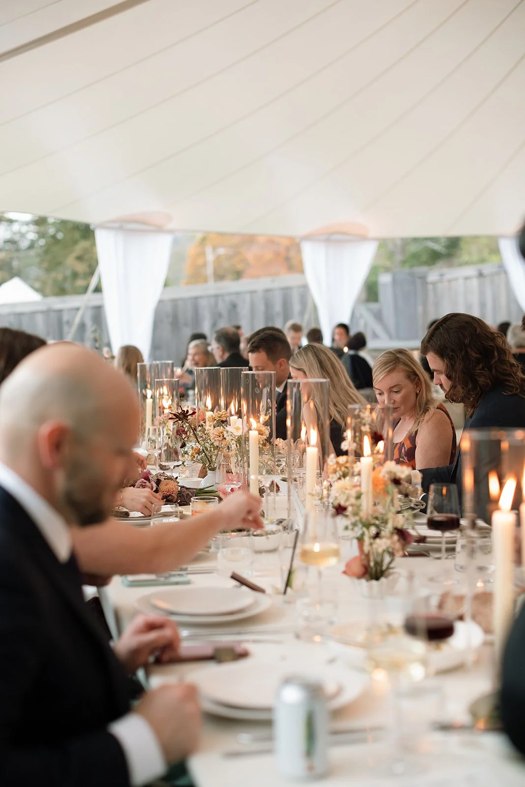 Long farm table styled with floral centerpieces, taper candles, and relaxed, organic place settings