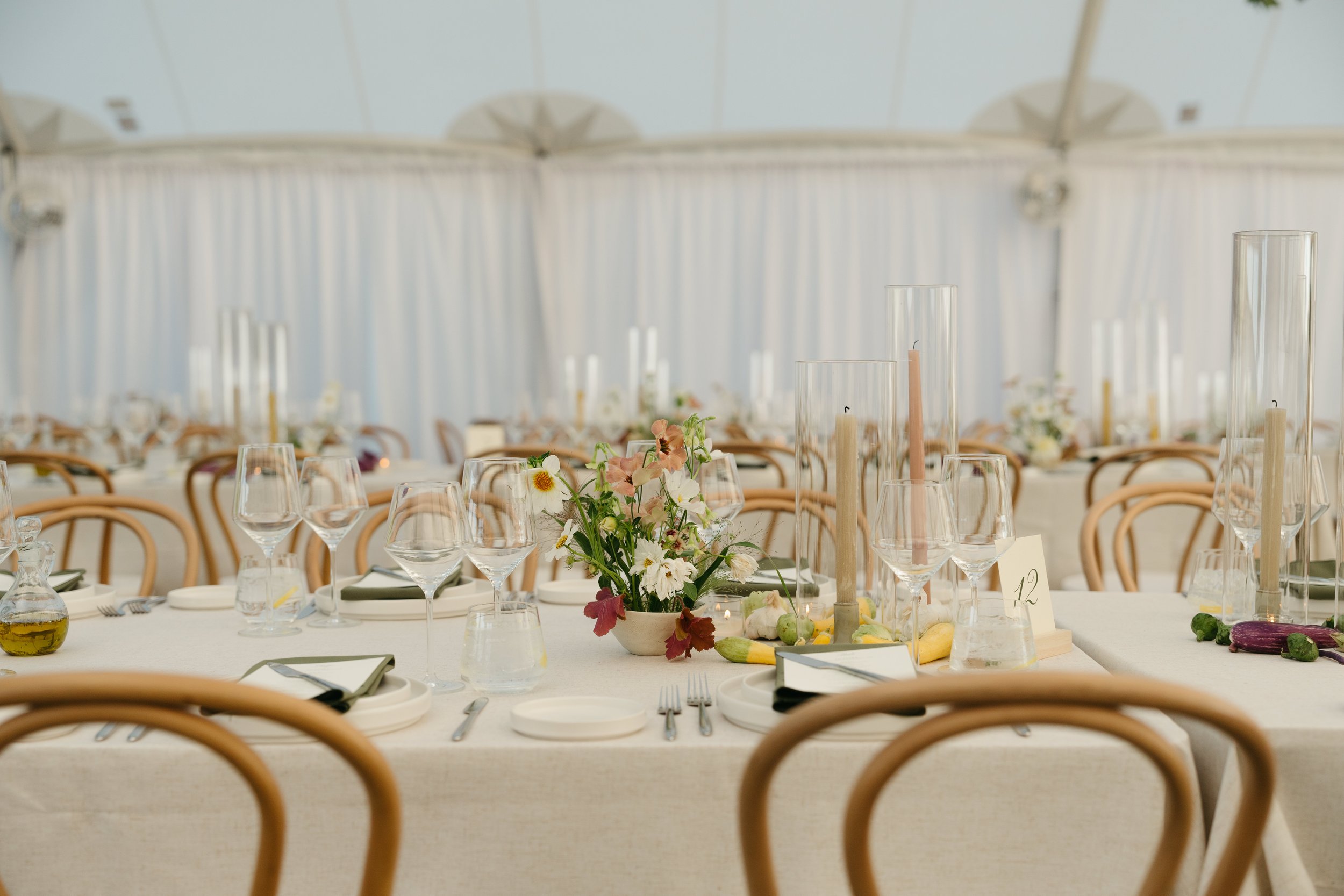 Low garden-style floral centerpiece with soft pink blooms and greenery on long reception table