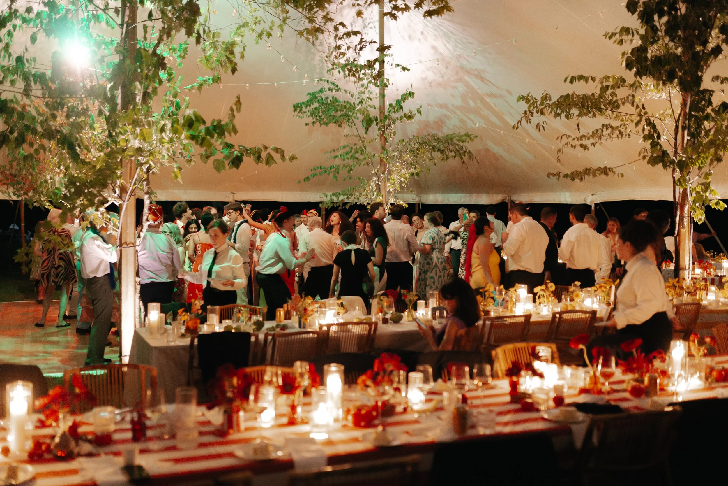 Evening reception under sailcloth tent with candlelit tables and guests dancing at private estate wedding