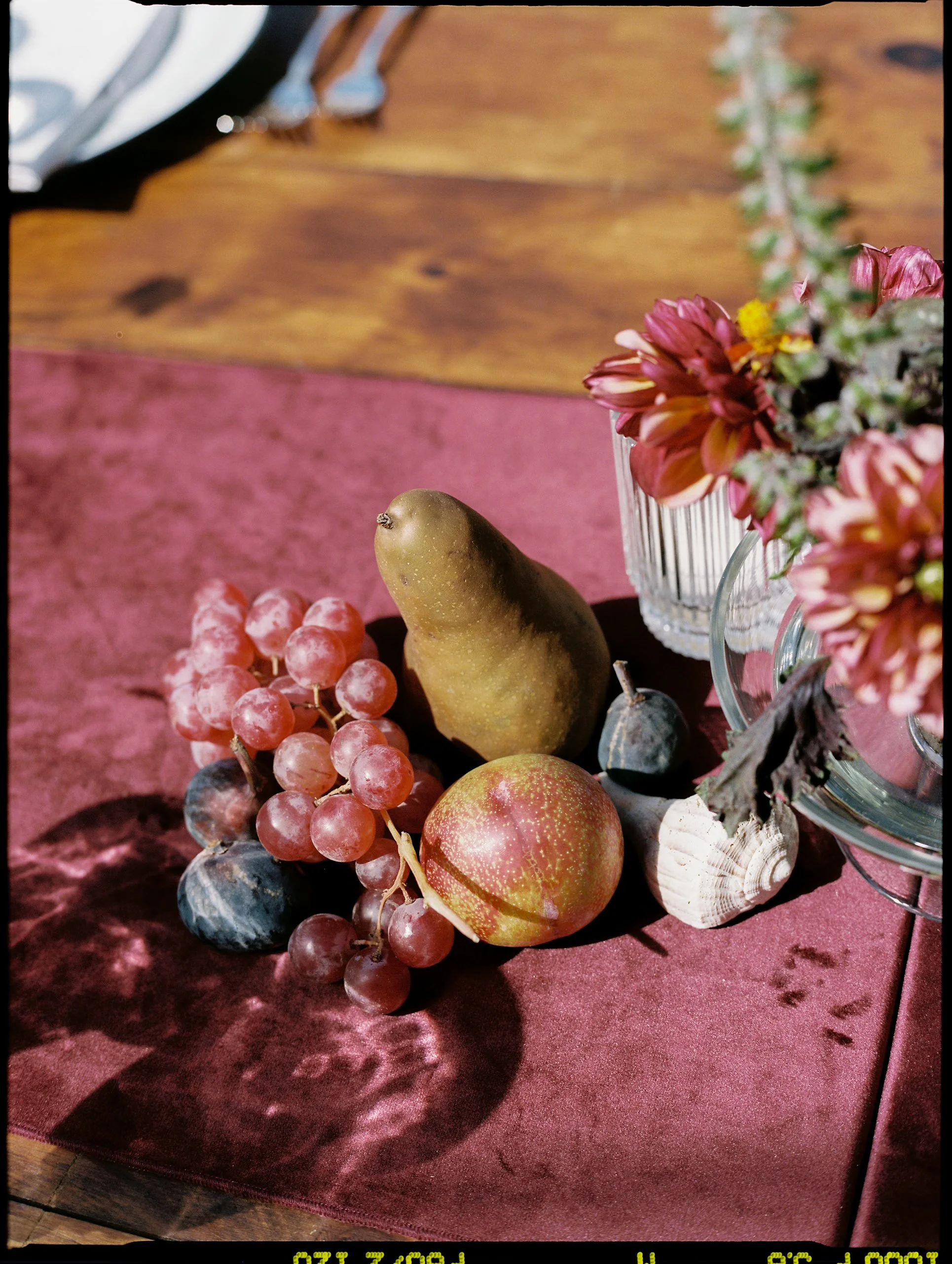 Tablescape detail featuring pears, grapes, and floral stems woven into the centerpiece design
