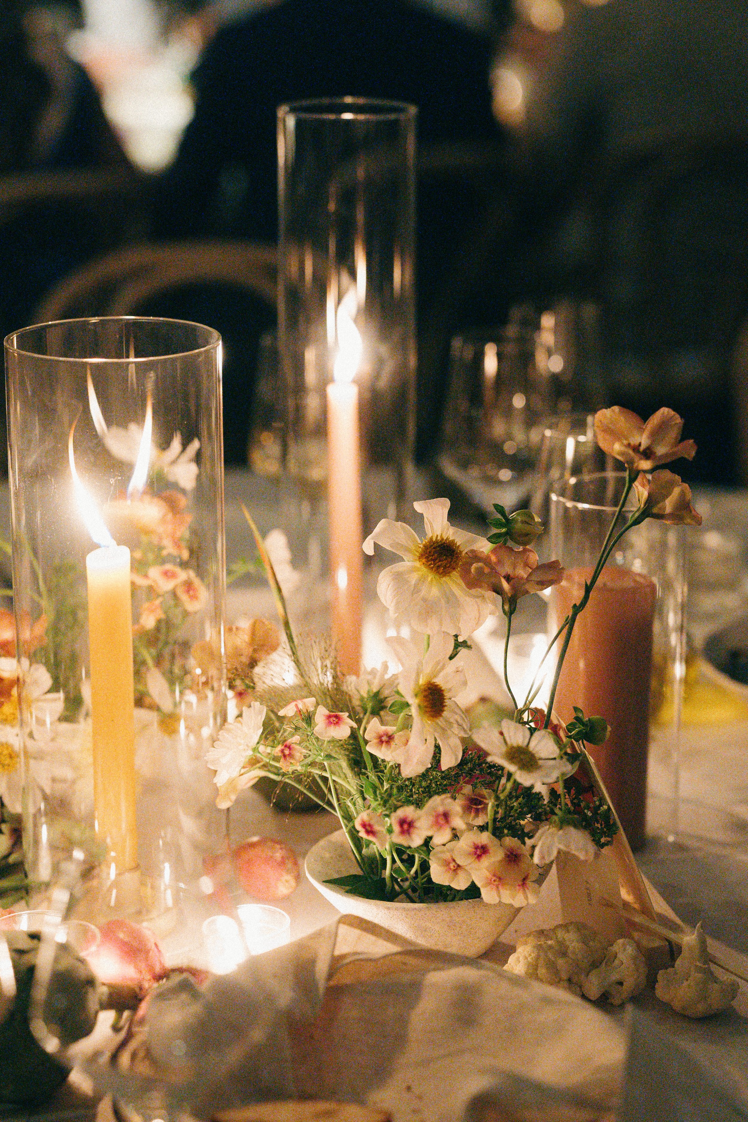 Candlelit floral centerpiece with soft blooms and greenery on dinner table