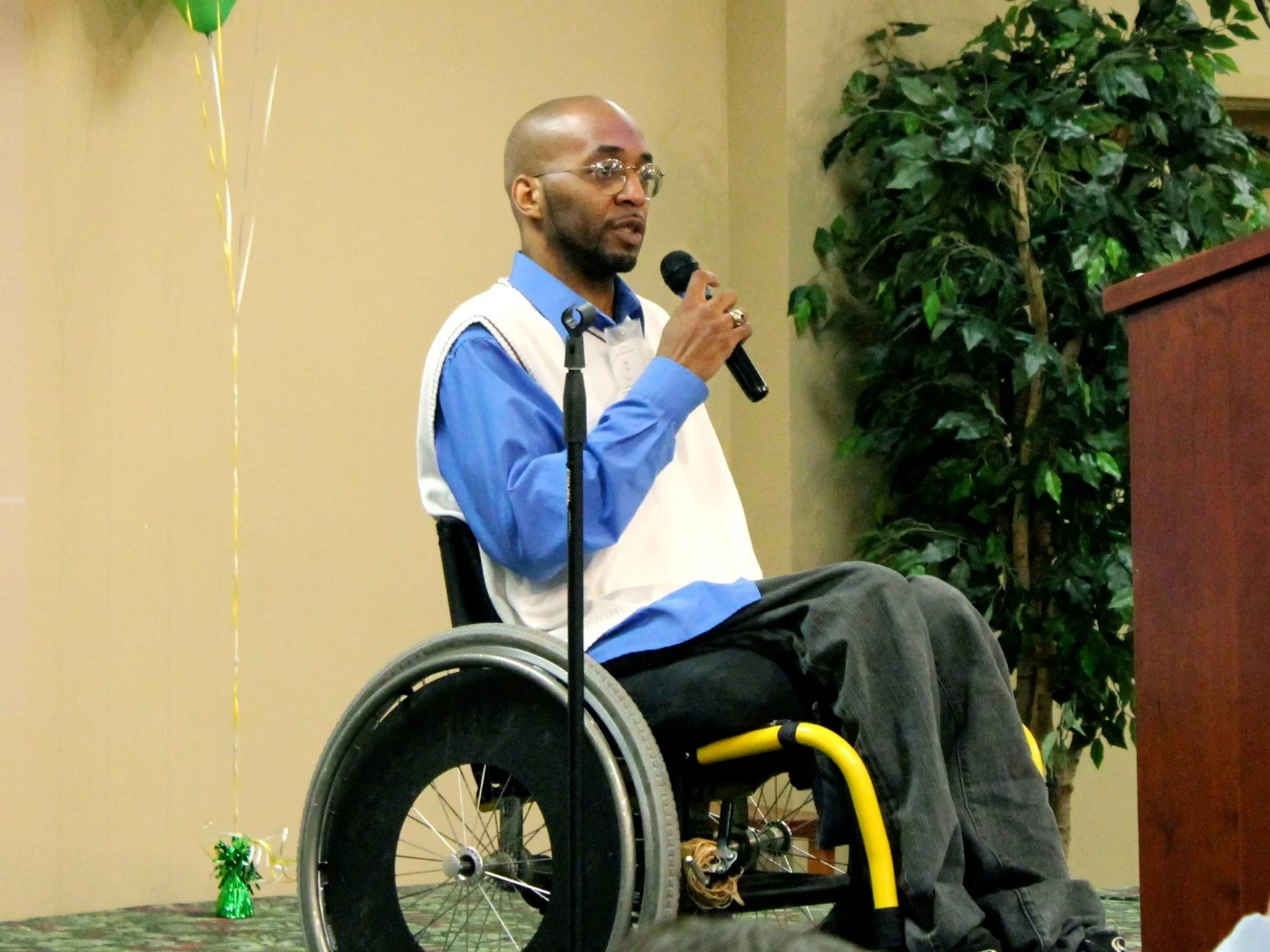 A Rush Home Tenant, in a wheel chair, speaks about the impact of the organization has had in his life in front of a crowd.