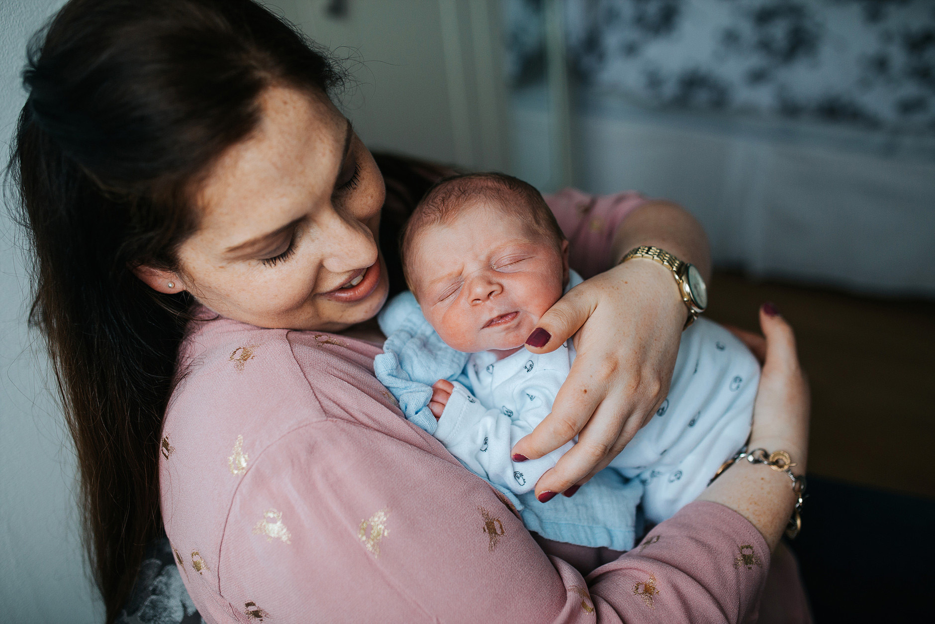 New mother cuddling her newborn baby at home