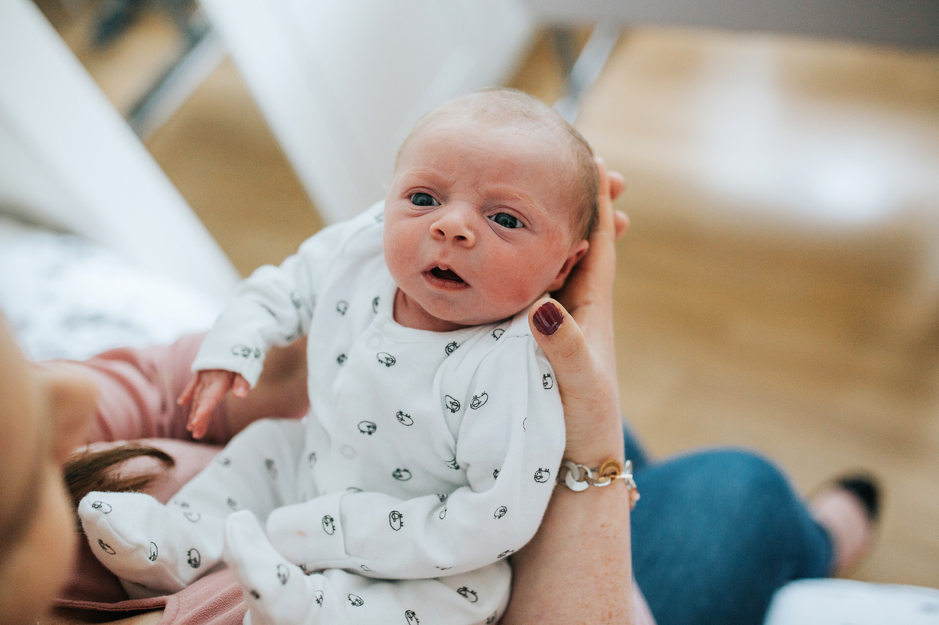 Newborn baby looks up at his mother with wide open eyes