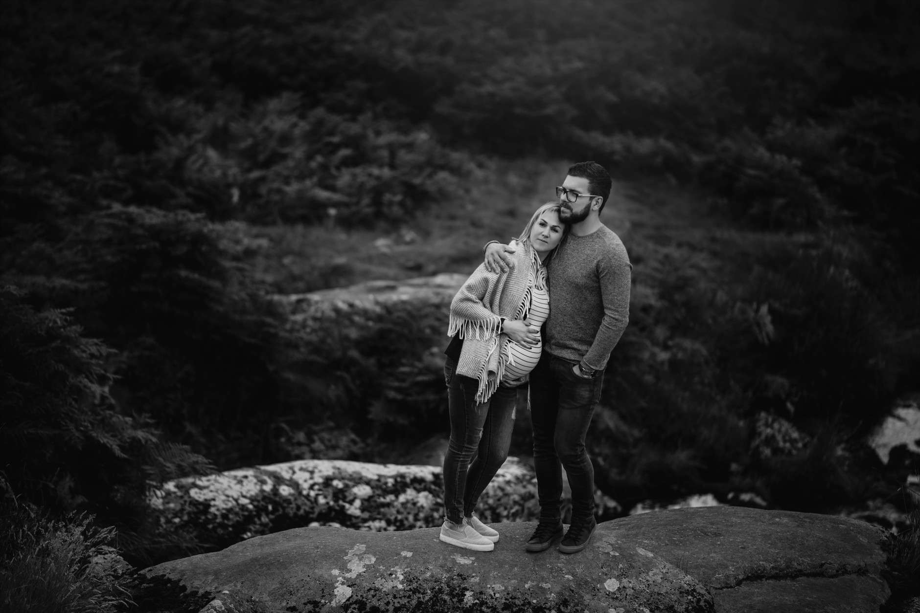 Pregnant woman leaning against her husband and touching her belly