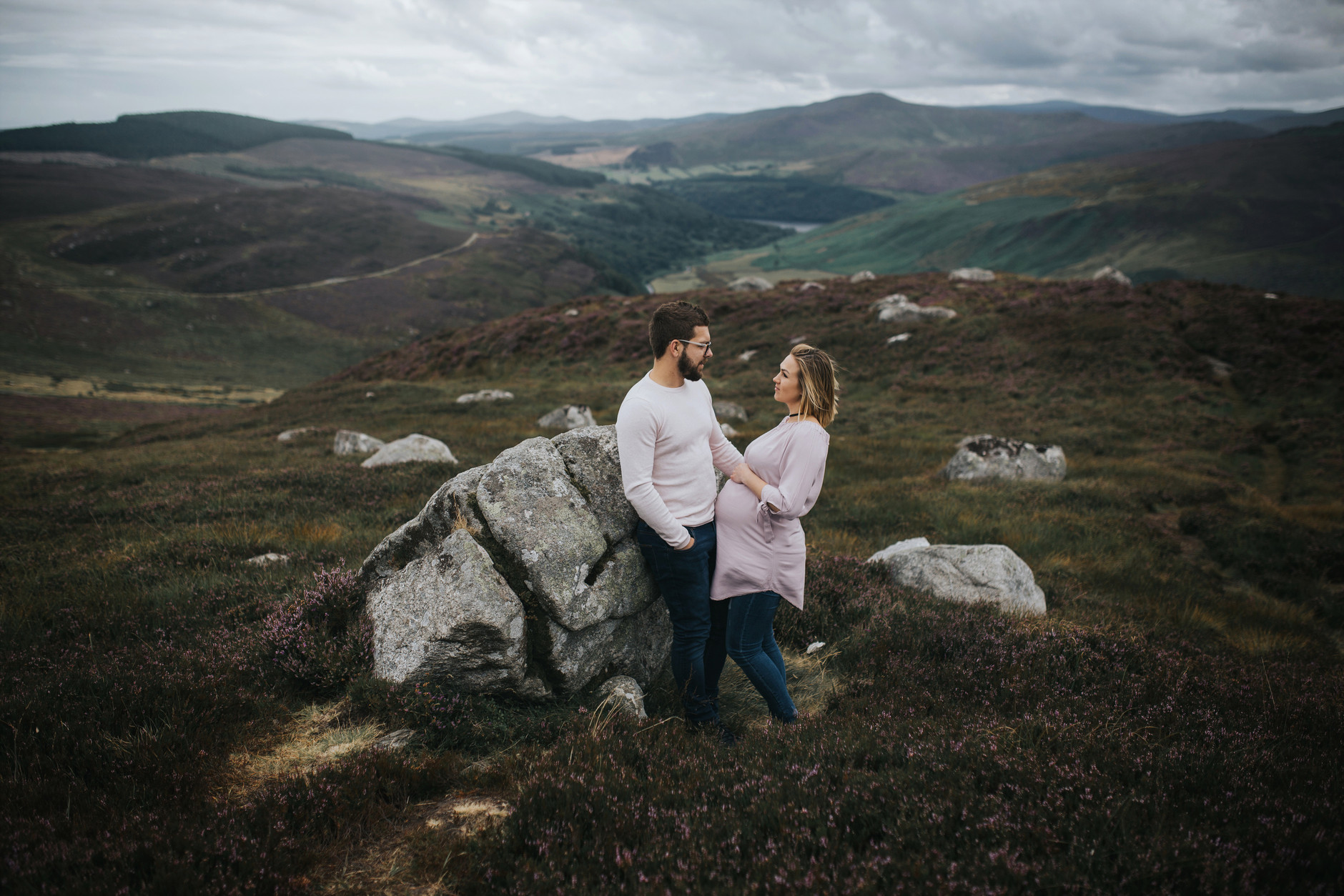 Expecting couple looking at each other in front of an amazing dublin mountains landscape