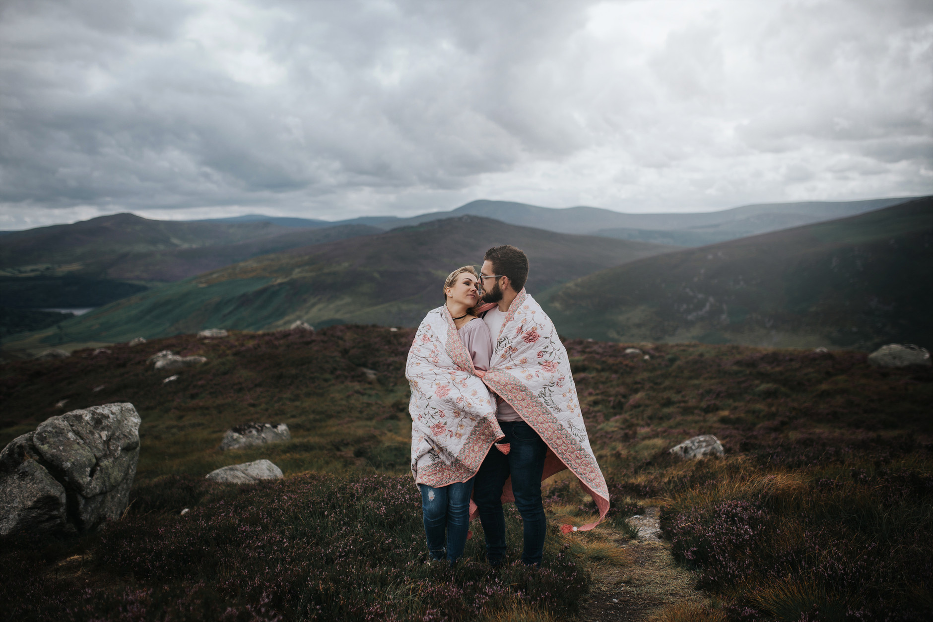 Couple wrapped in a blanket in front of scenic irish landscape