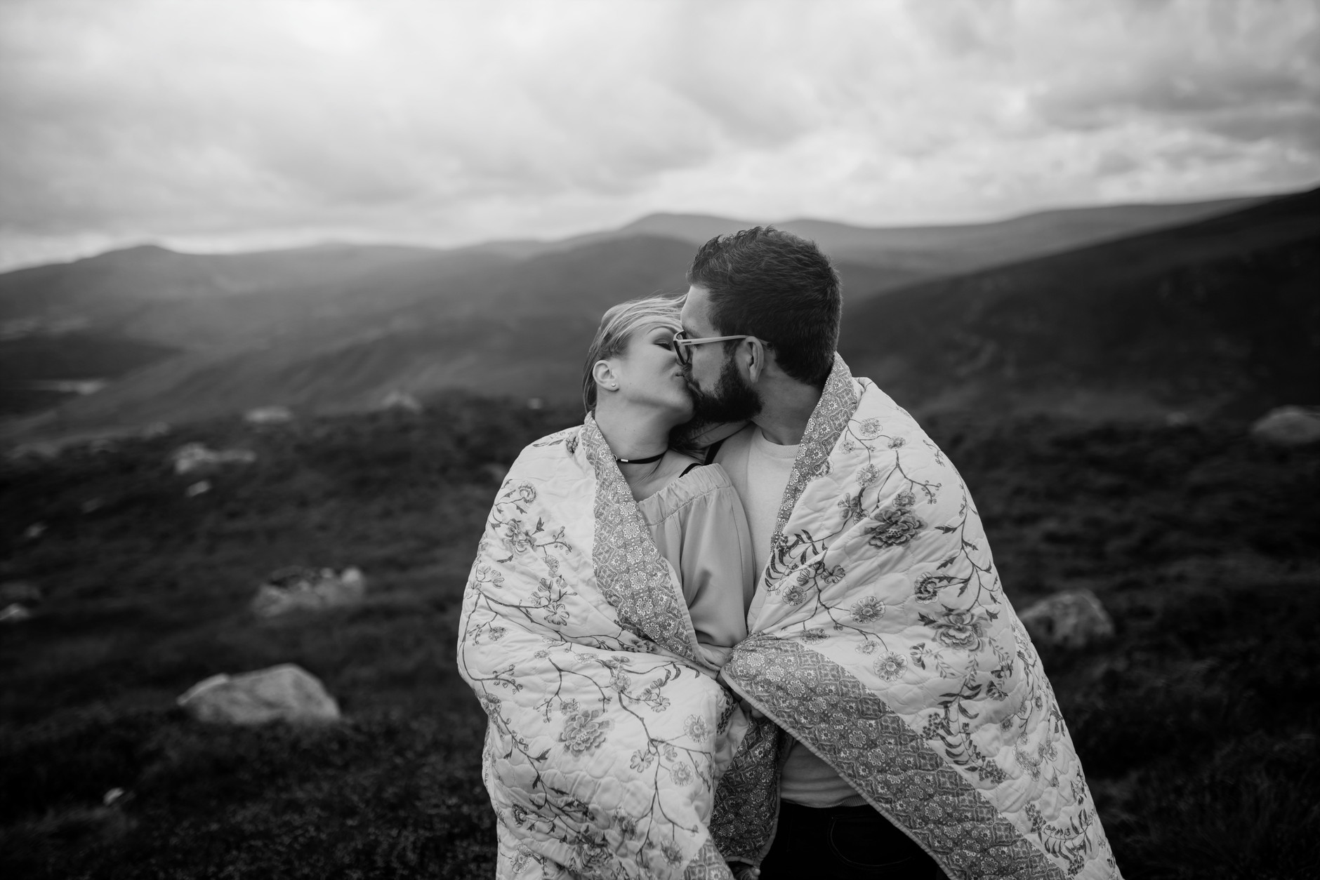 Stunning black and white photograph of couple kissing in front of mountains