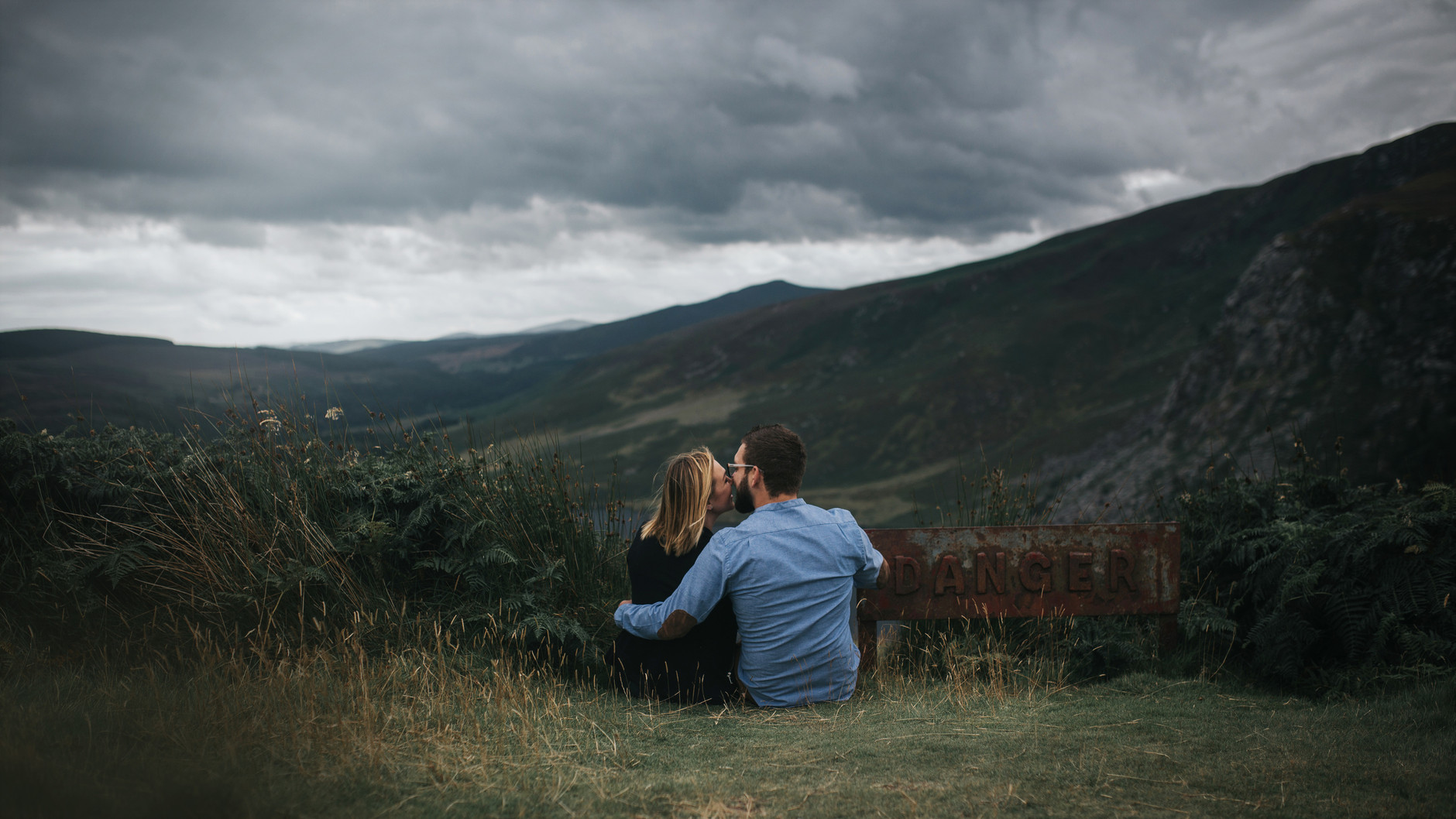 Couple sitting on the ground kissing in front of scenic view