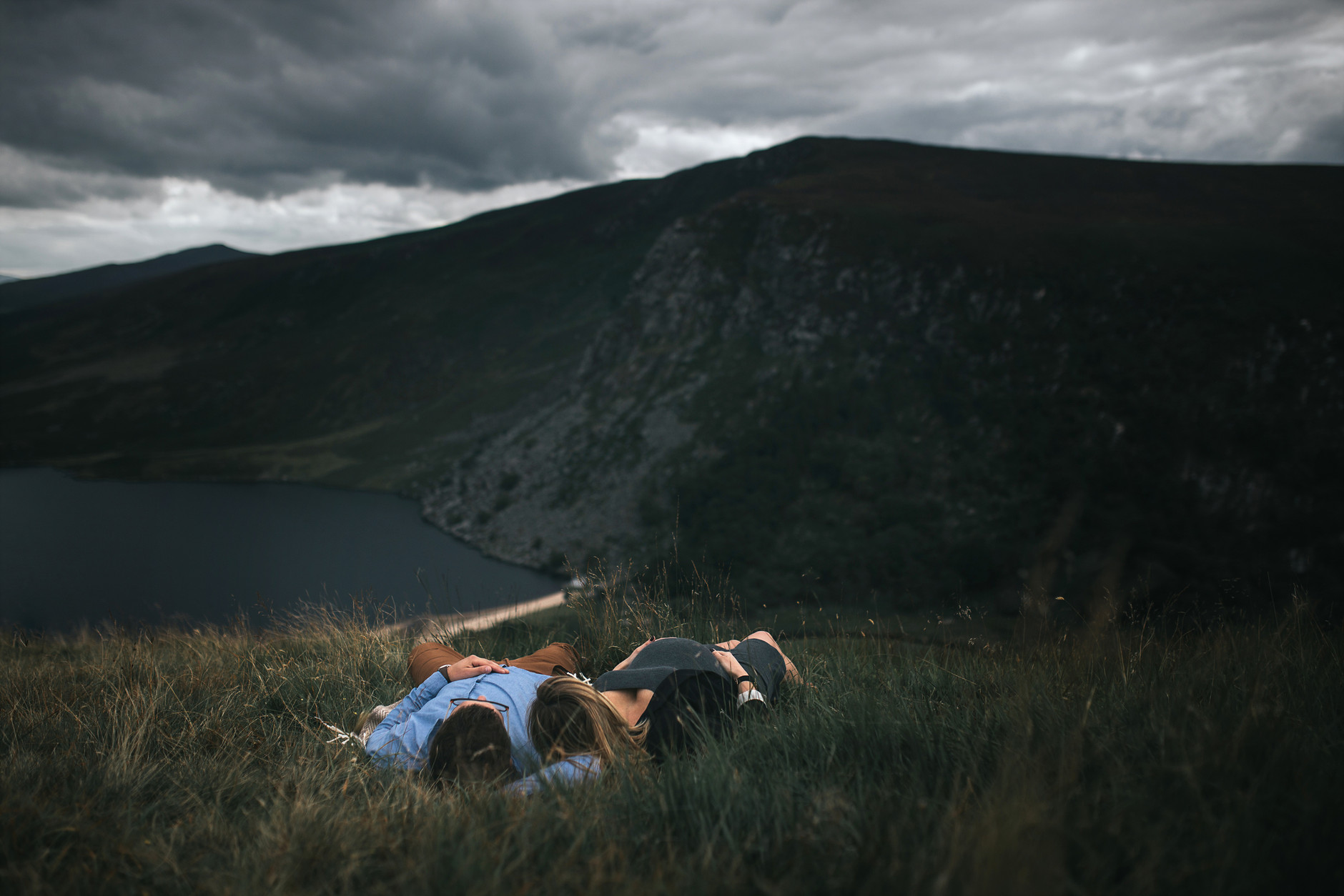Couples lying in the high grass in front of mountain and beautiful lake