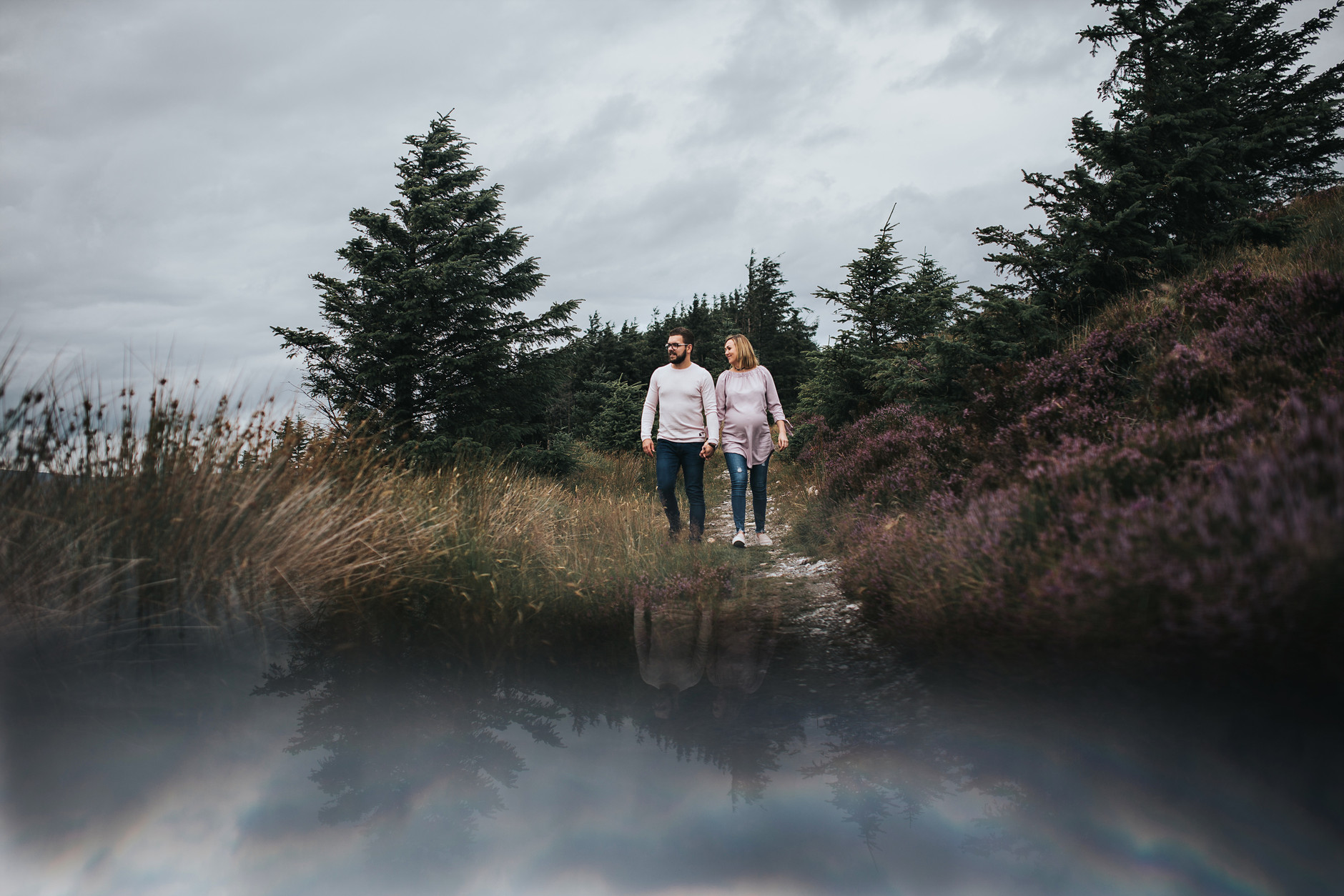 Expecting couple walking hand in hand in the beautiful irish landscape