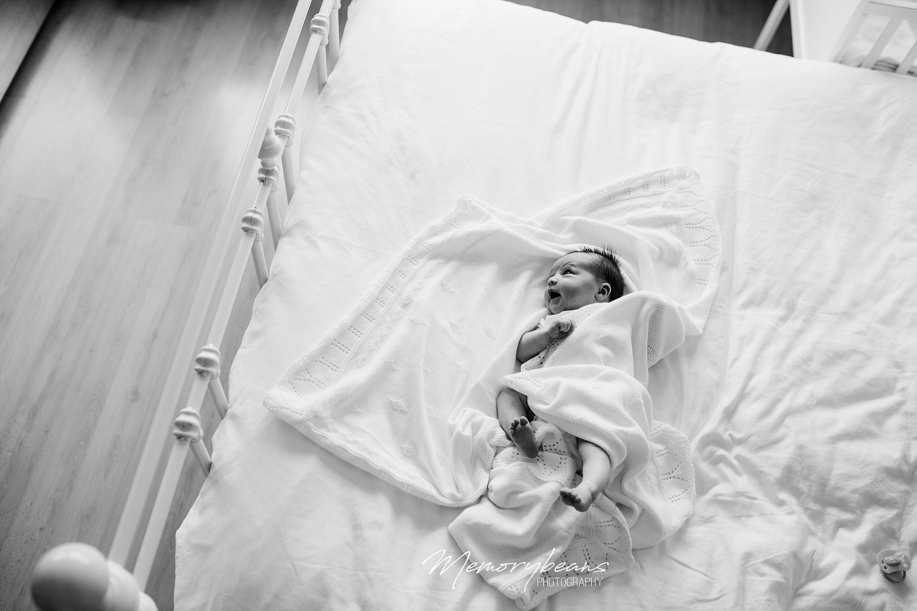 Newborn baby wide awake lying on the big bed