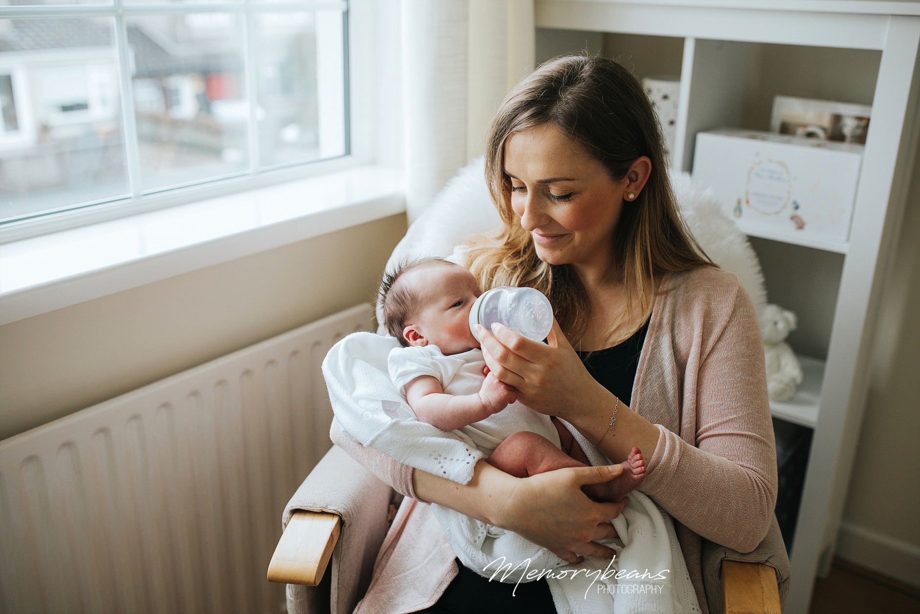 New mother smiling while feeding her newborn baby a bottle