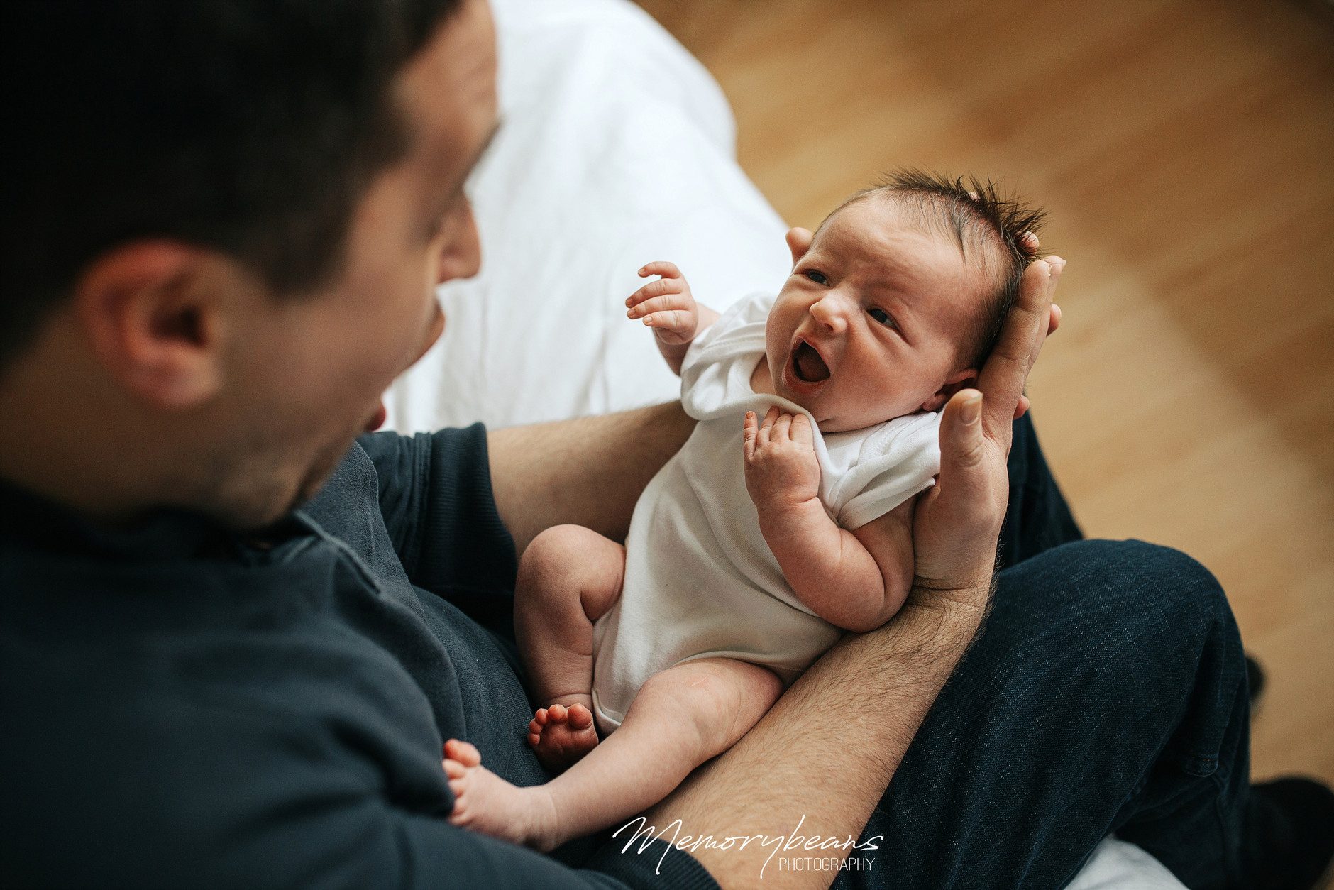 Newborn baby held by father with the same expression