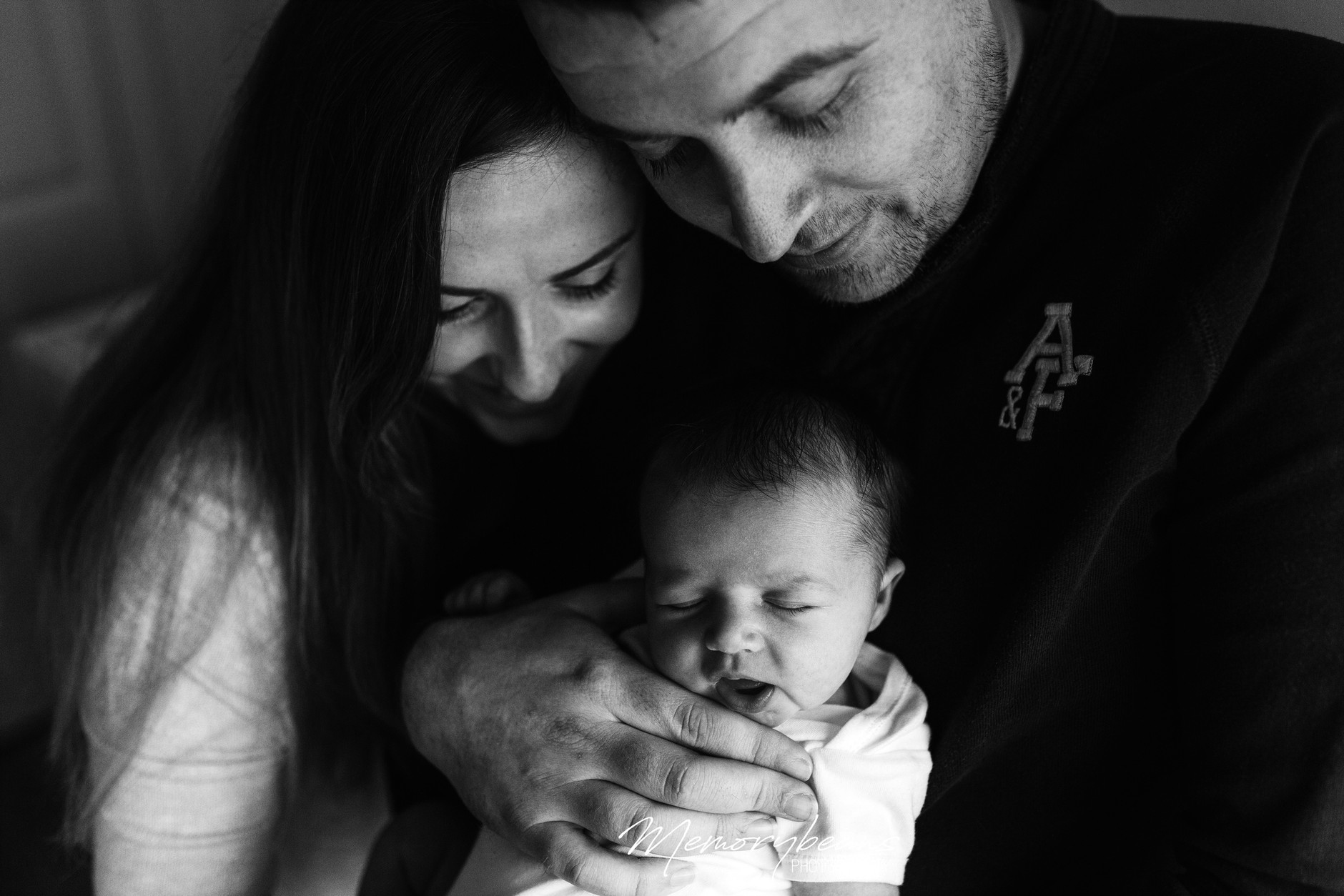 Black & White Photograph of Father and mother holding their sleeping newborn baby