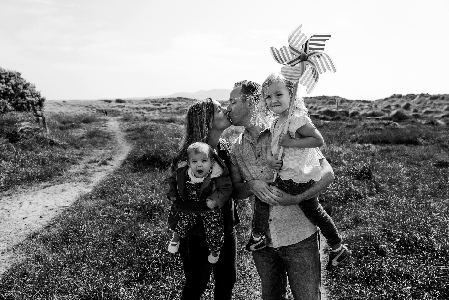 Parents kissing and holding their two girls during their vacation photoshoot in Dublin