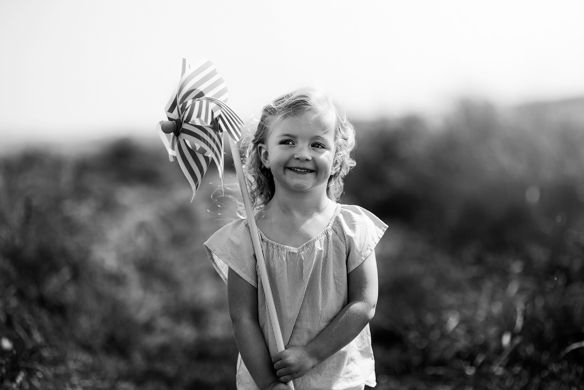 Little girl smiling and holding a wind mill in the sand dunes