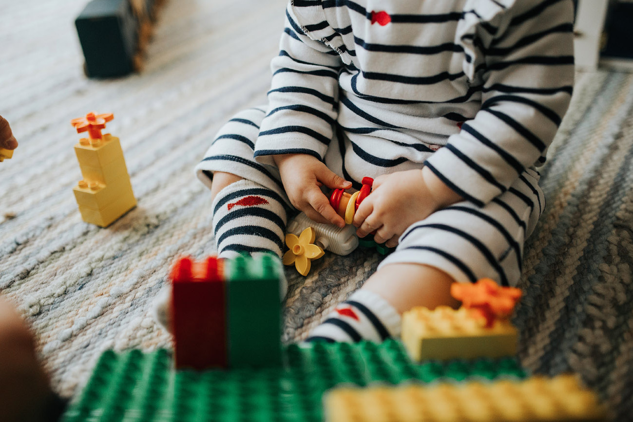 Detail of toddler’s hands playing with legos