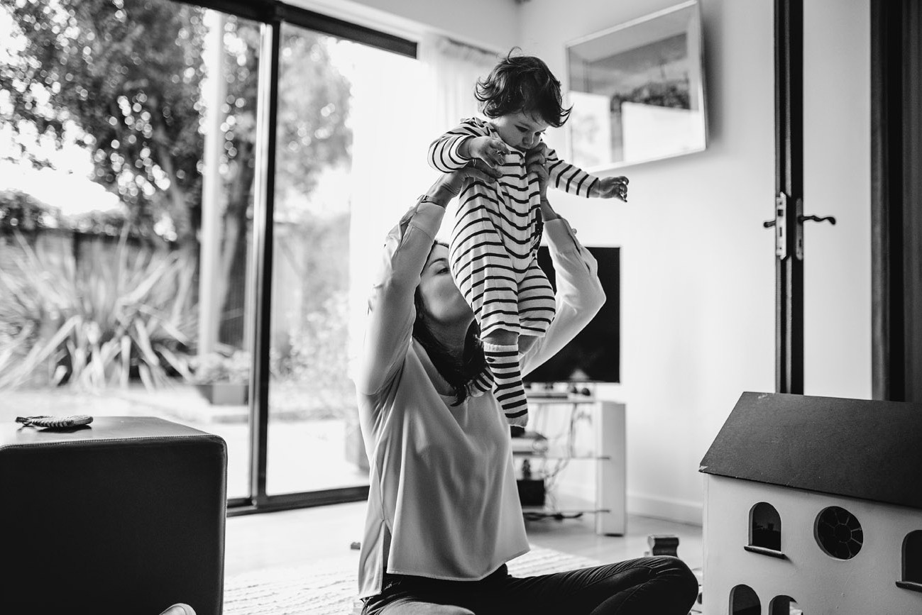 Mother lifting her son in the air to smell his bum / nappy