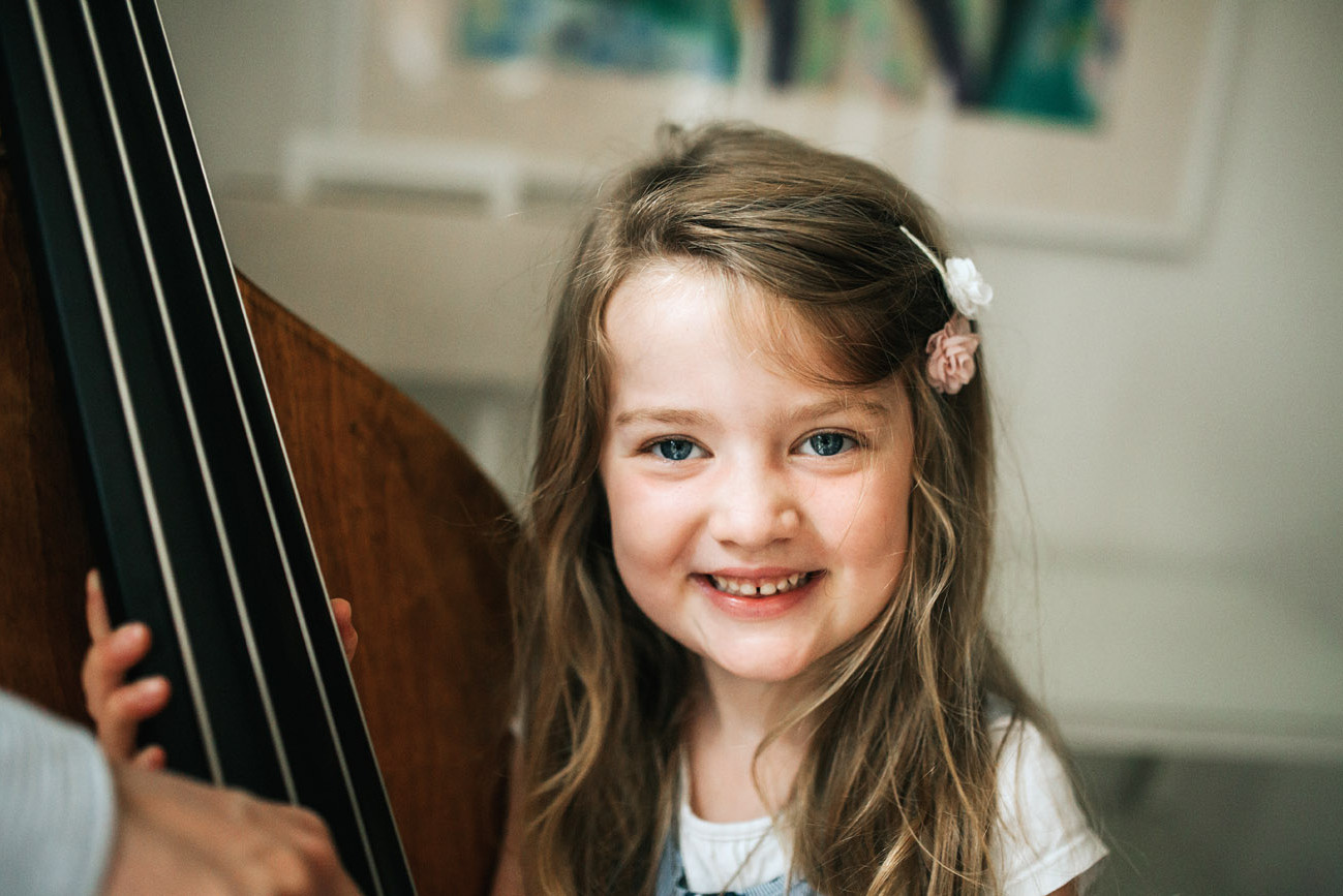 Little girl looking and smiling at the camera beside a music instrument