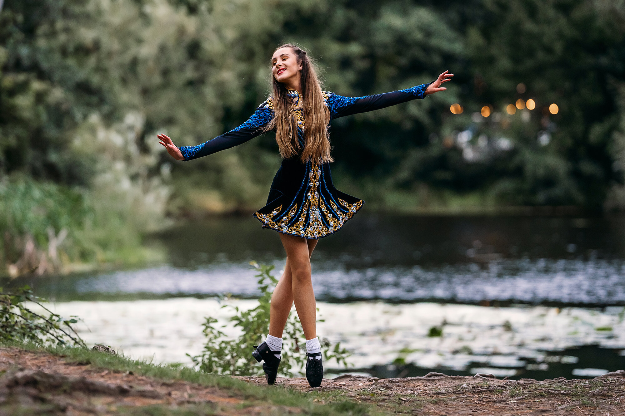 Irish dancer in dancing costume standing beside the lake