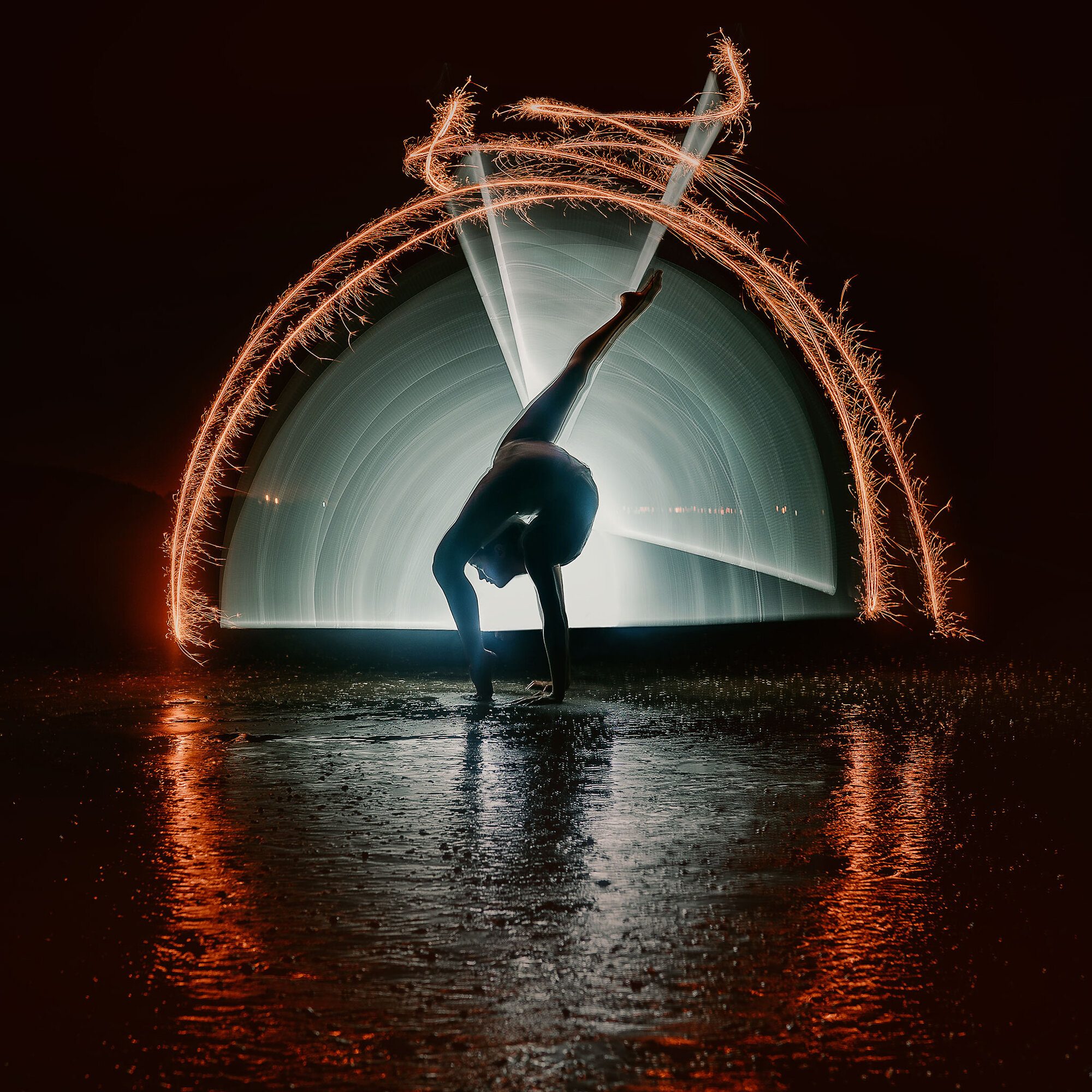 acrobatic performer on the beach at night with light painting
