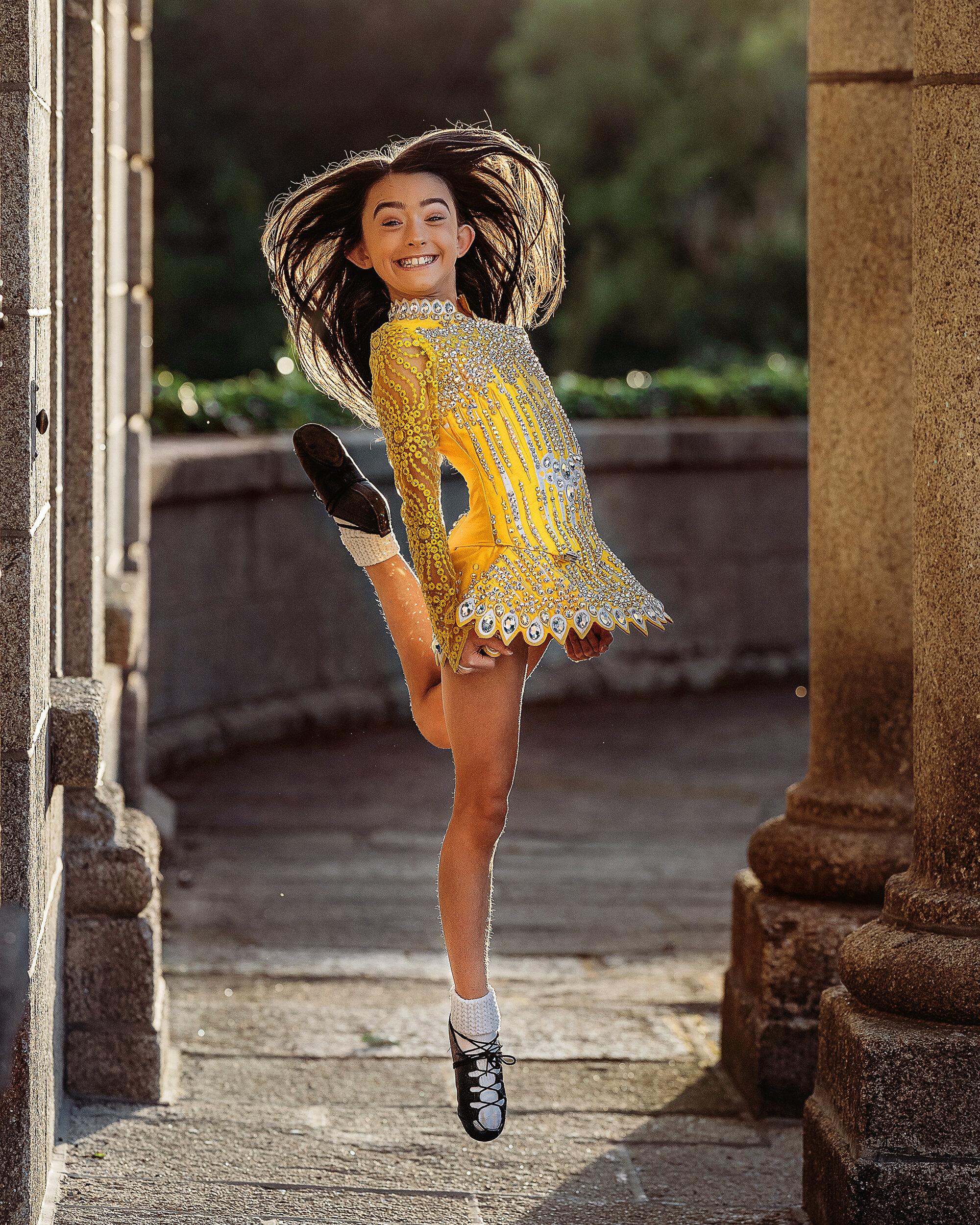 young Irish dancer in sparkling dance dress leaping in the sun