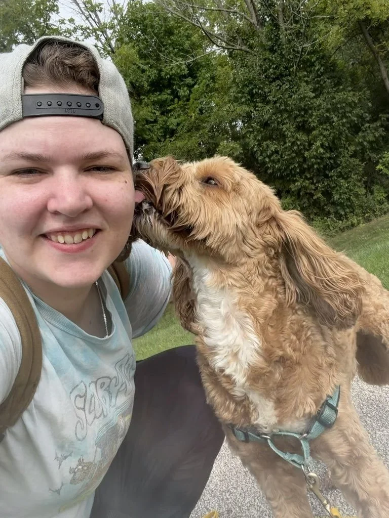 Kayla, a member of the Off Leash MKE team, receives kisses from a dog