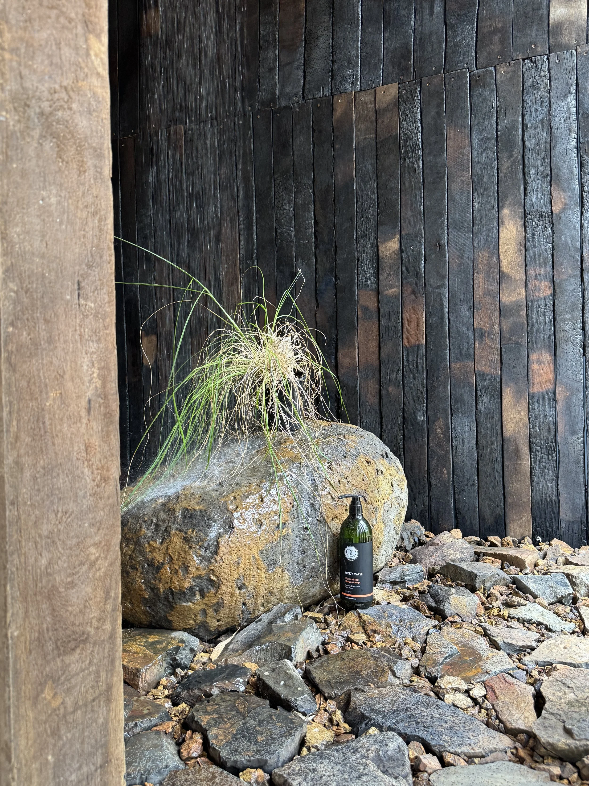 Entrance to the plonc. Goodnight Studio in Queensland, featuring charred timber cladding, natural stone, handcrafted Japanese ceramic vessel and landscaped garden expressing the studio's material philosophy.