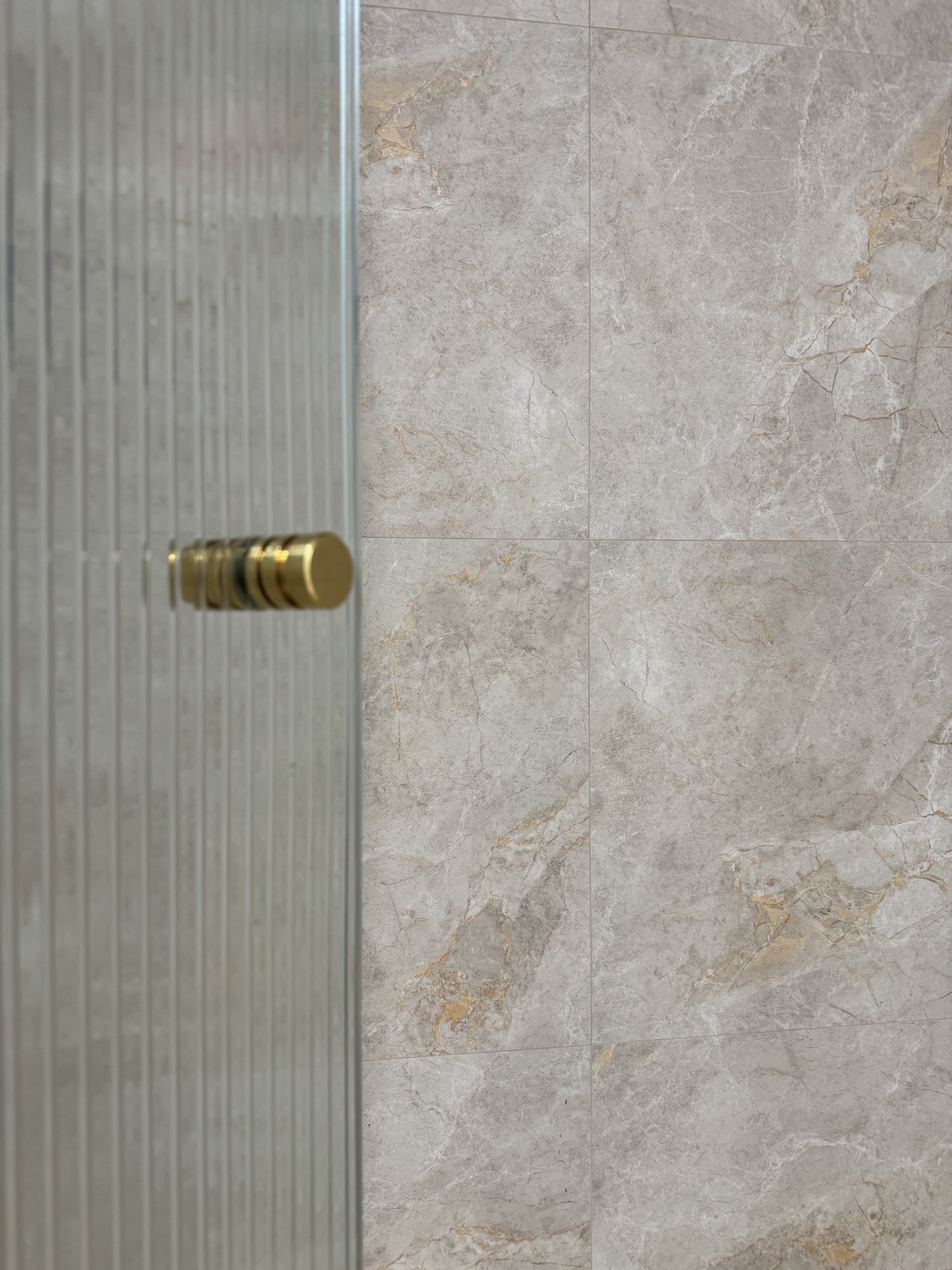 Bathroom interior featuring Sunset by plonc., an authored large format porcelain surface with subtle relief and warm mineral tones on walls.