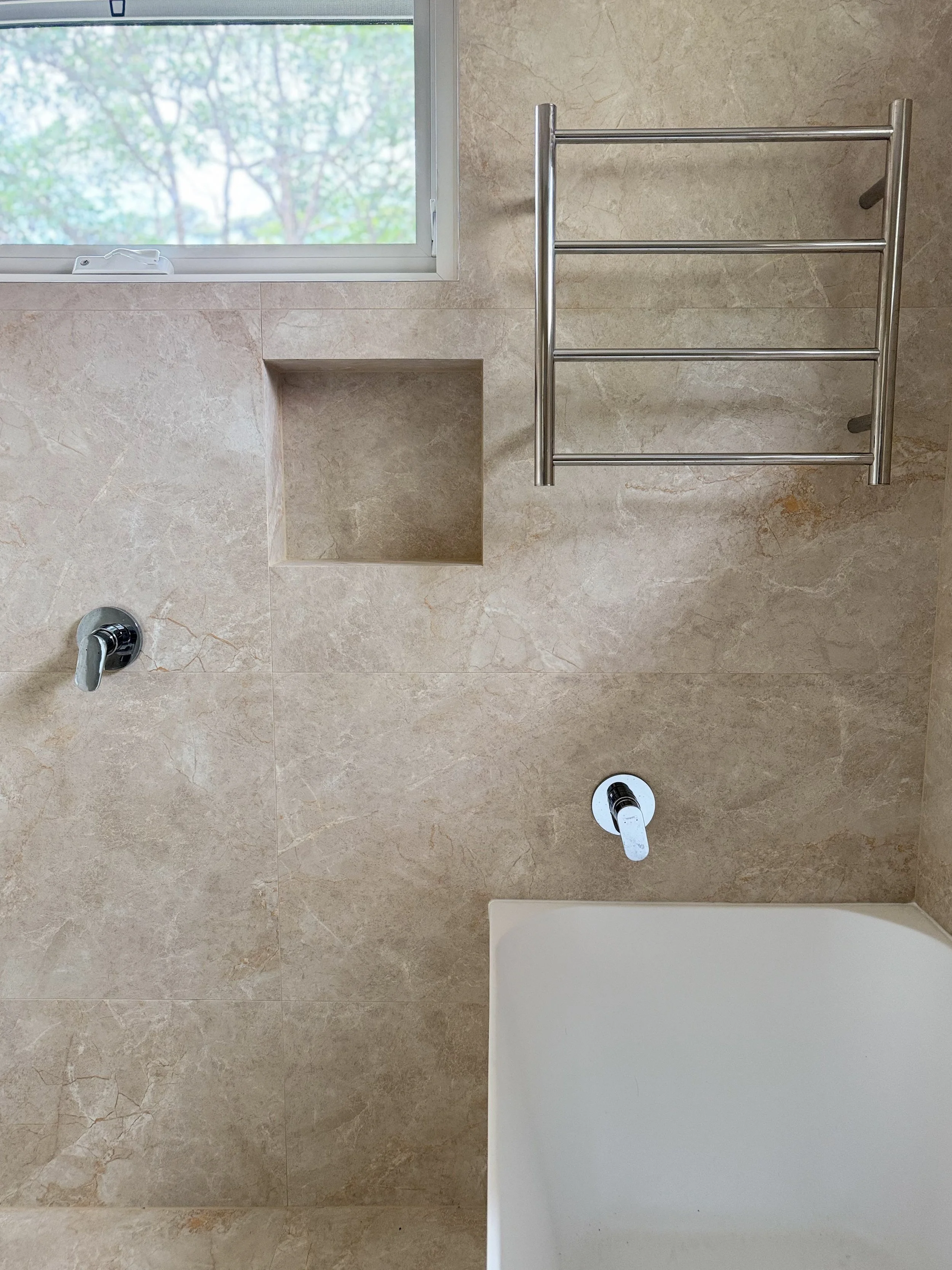 Bathroom interior featuring Sunset by plonc., an authored large format porcelain surface with subtle relief and warm mineral tones on walls.