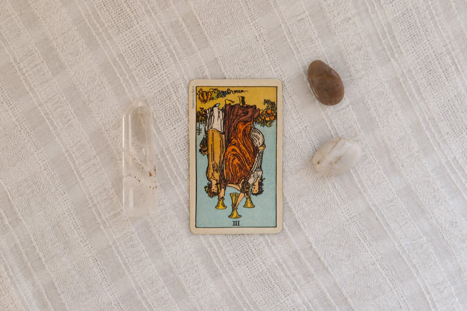 Three figures dancing and celebrating together, representing the joyful bonds of friendship and love in the Three of Cups tarot card