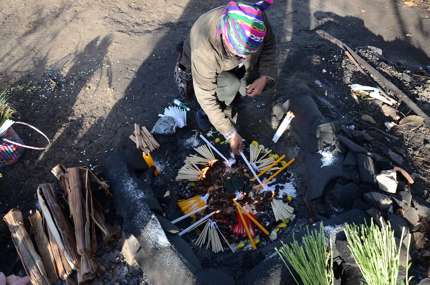 Figure 12. K'iche' ajq'ij beautifully organizing offerings to be burned in the ceremonial fire, Momostenango. Photo by Dimitris Xygalatas.