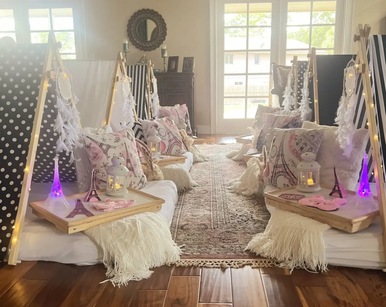 Paris-themed kids’ sleepover setup with decorated teepee tents, pillows and party décor.