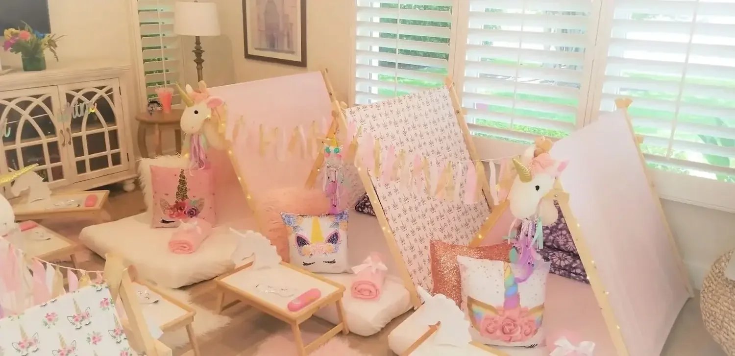 Kids’ sleepover party setup with themed tents, pillows, flowers and decorative trays.