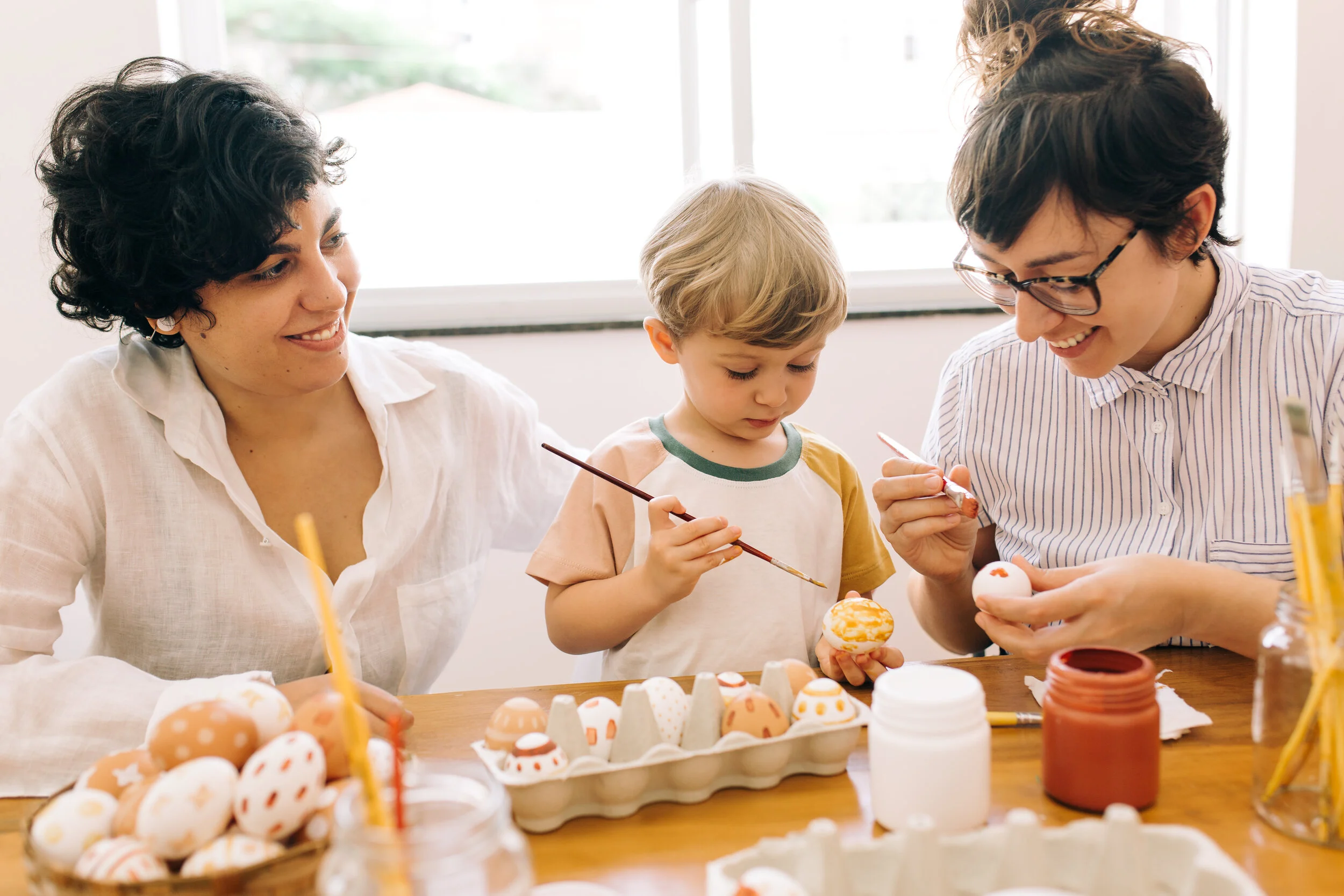 A model child painting eggs with two models