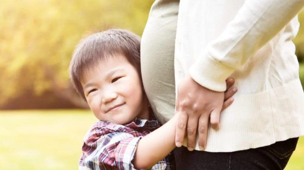 A model child hugging a model  pregnant woman