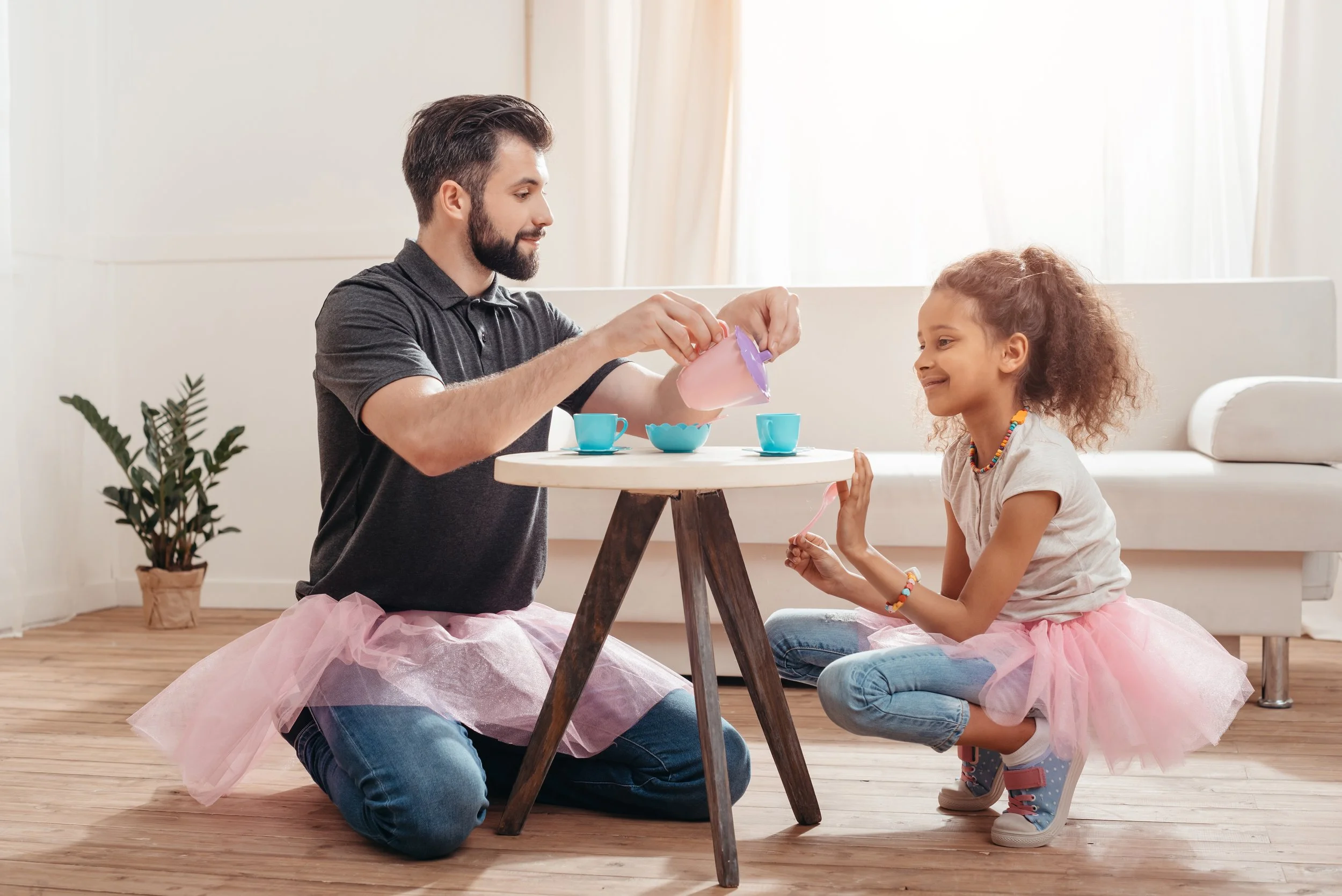 A man and a little girl sitting at a table, playing tea time